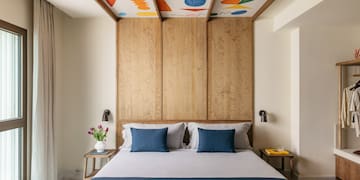 a bed with blue pillows and a wood paneled ceiling