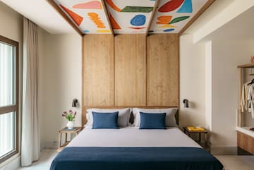 a bed with blue pillows and a wood paneled ceiling