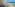 Vistas desde balcón a playa, mar azul, palmeras y piscina.