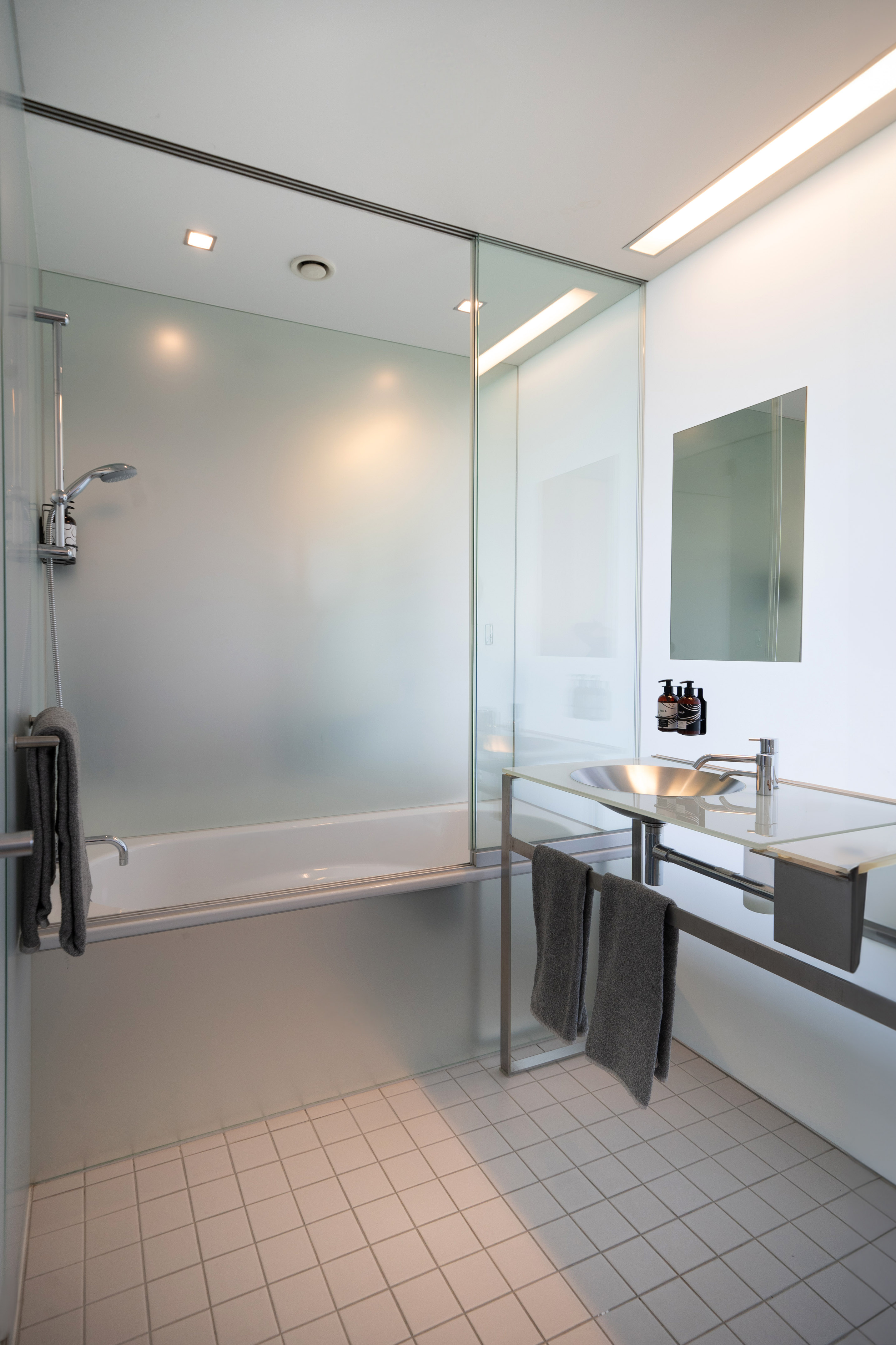 Minimalist modern bathroom with glass shower, integrated bathtub, and vanity sink.