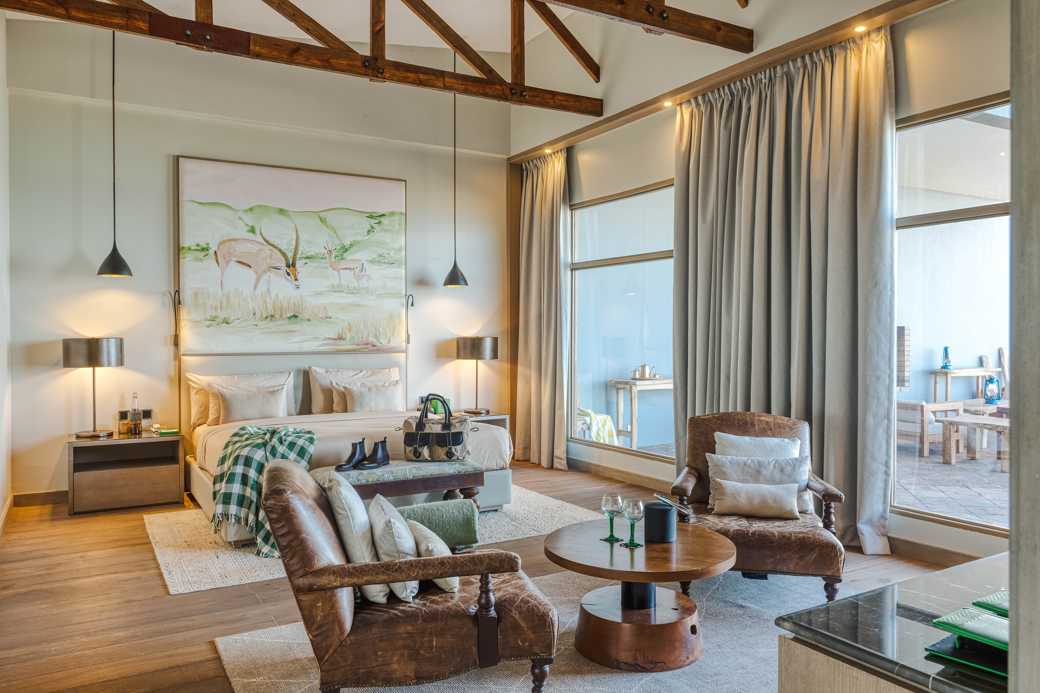African safari lodge suite with bedroom, lounge, and scenic view.