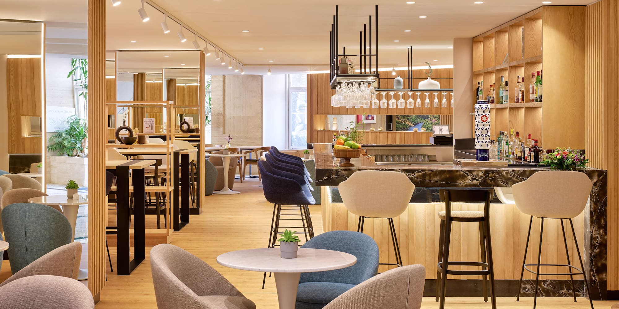 Bar de hotel moderno con barra de mármol, asientos y diseño en madera.