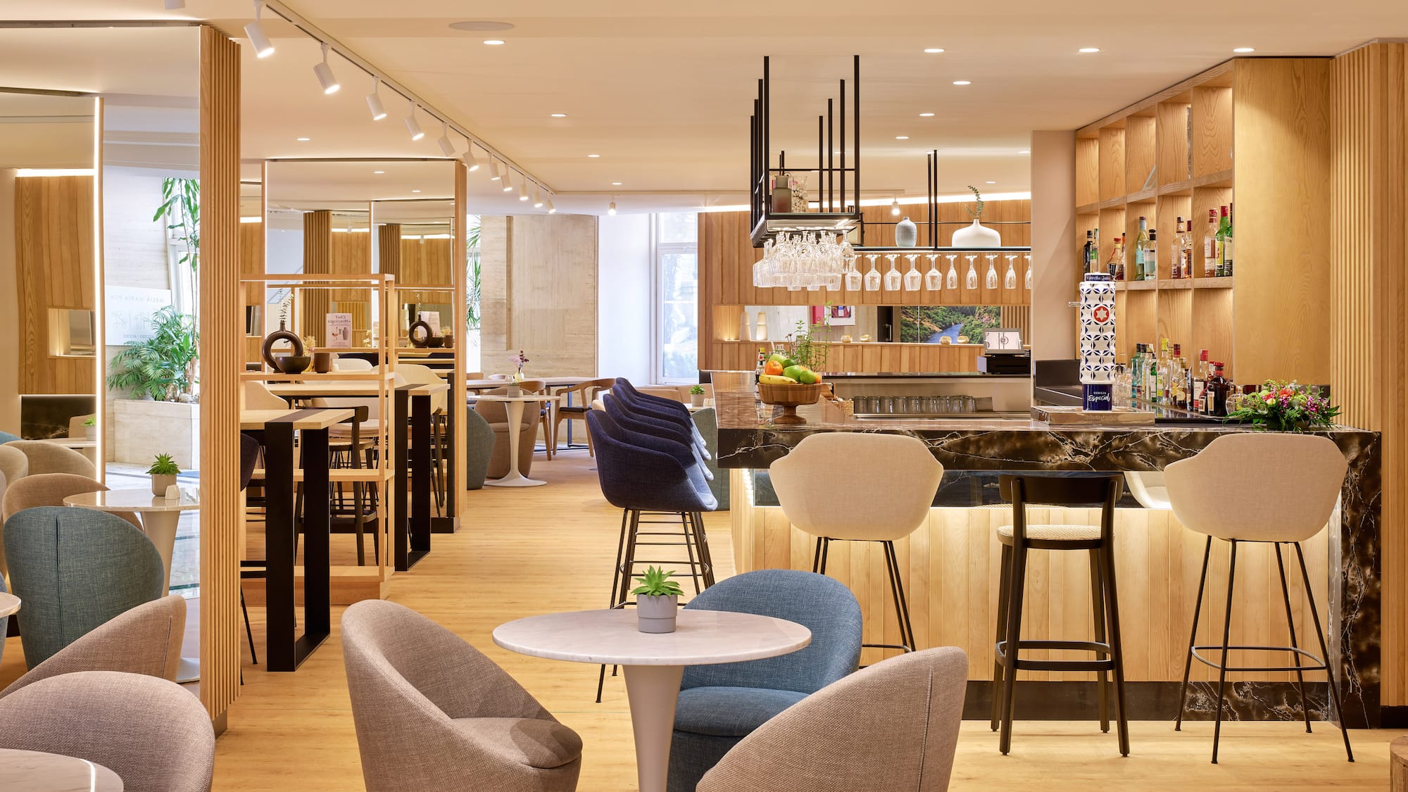 Bar de hotel moderno con barra de mármol, asientos y diseño en madera.