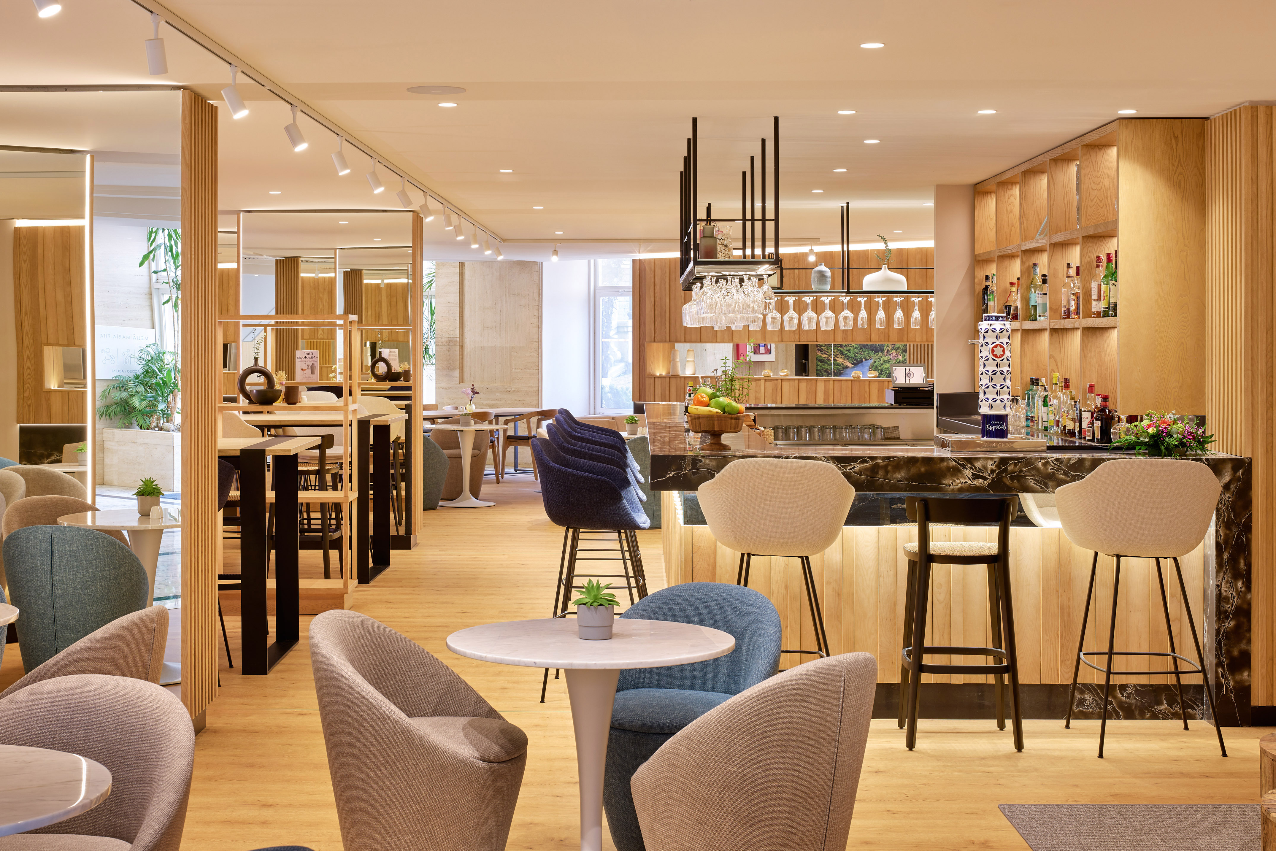 Bar de hotel moderno con barra de mármol, asientos y diseño en madera.