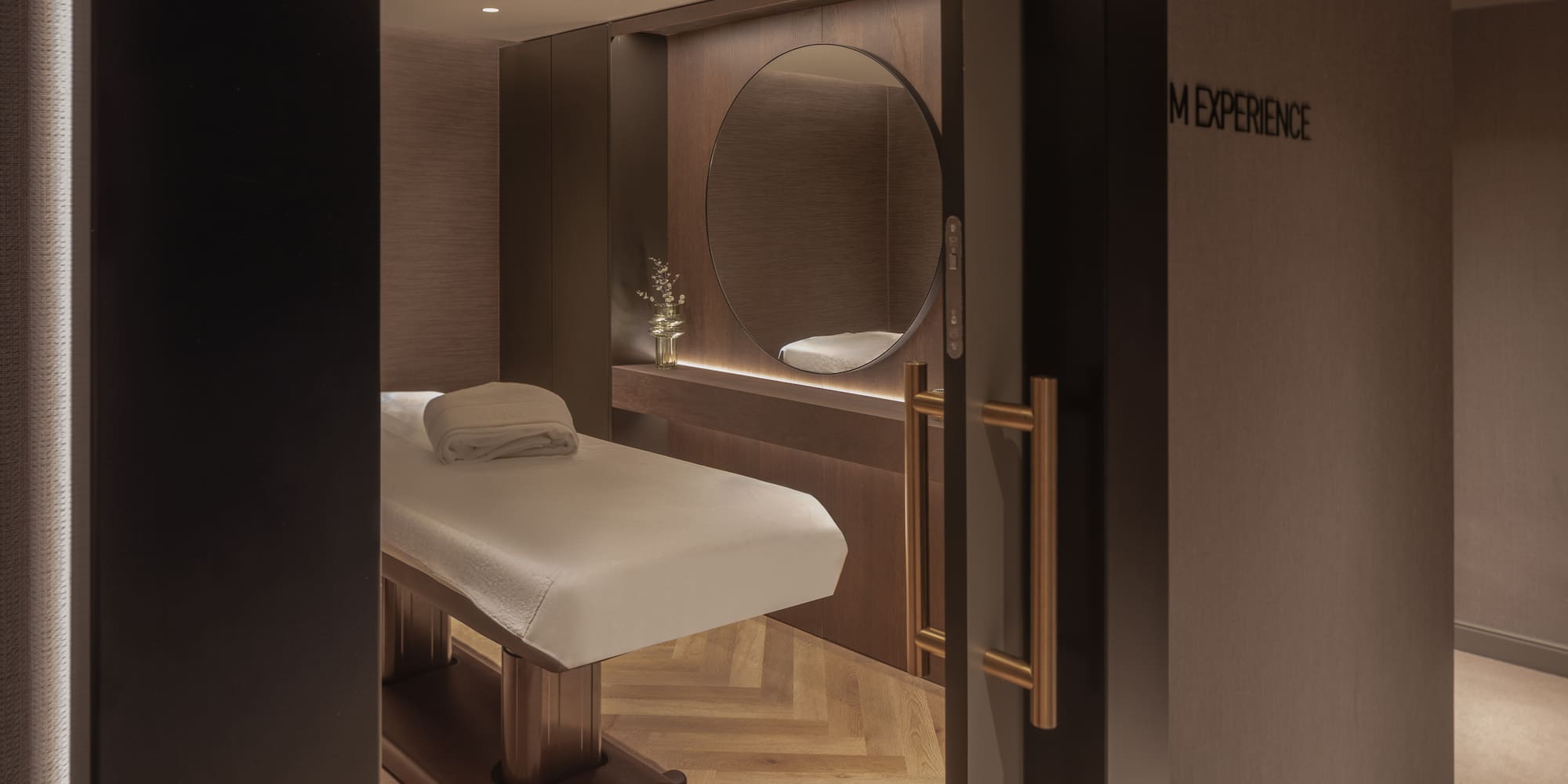Luxury spa treatment room with massage table, circular mirror, and warm lighting.