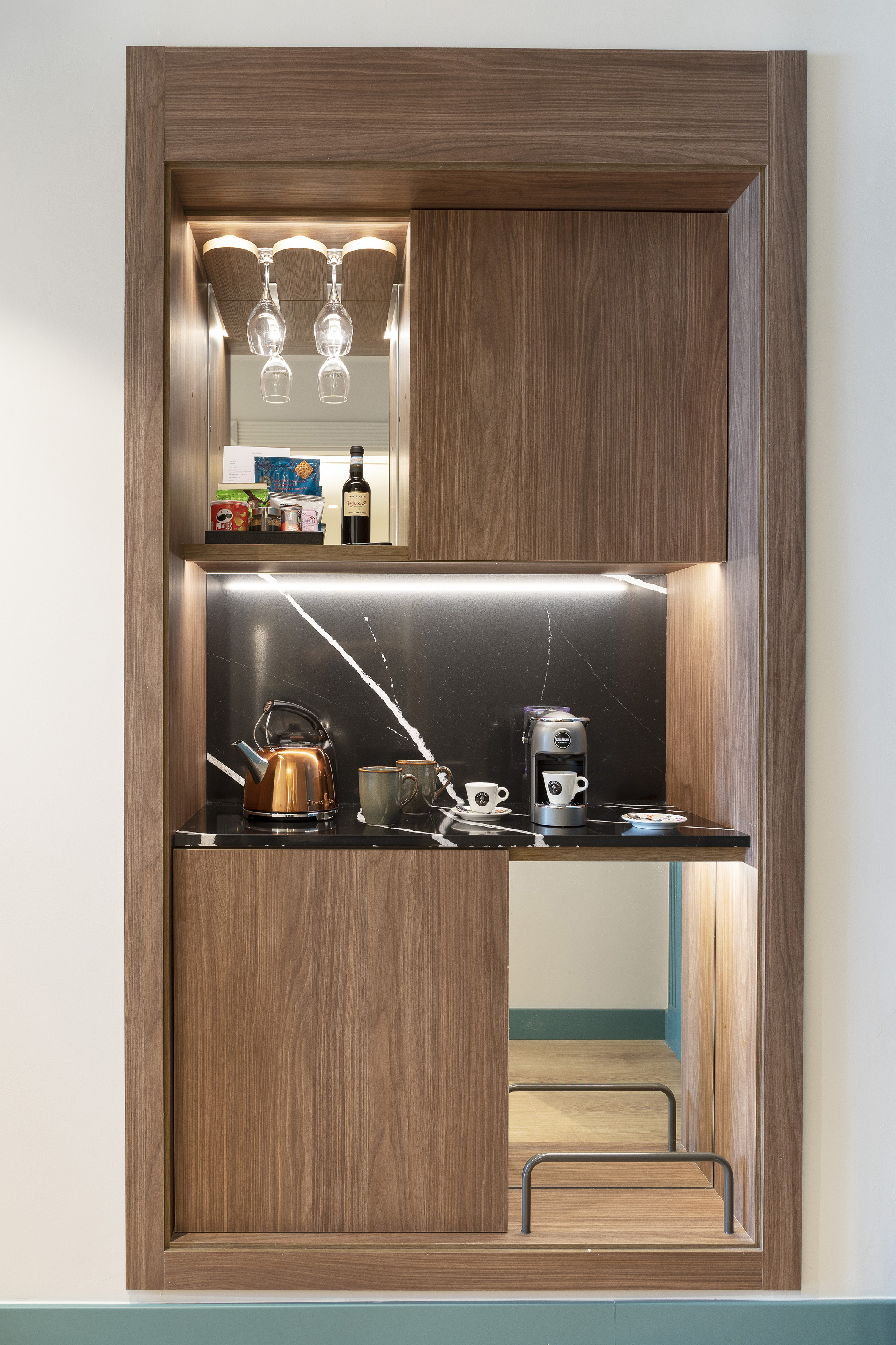 Hotel mini-bar coffee station: wood, marble, kettle, coffee maker, wine.