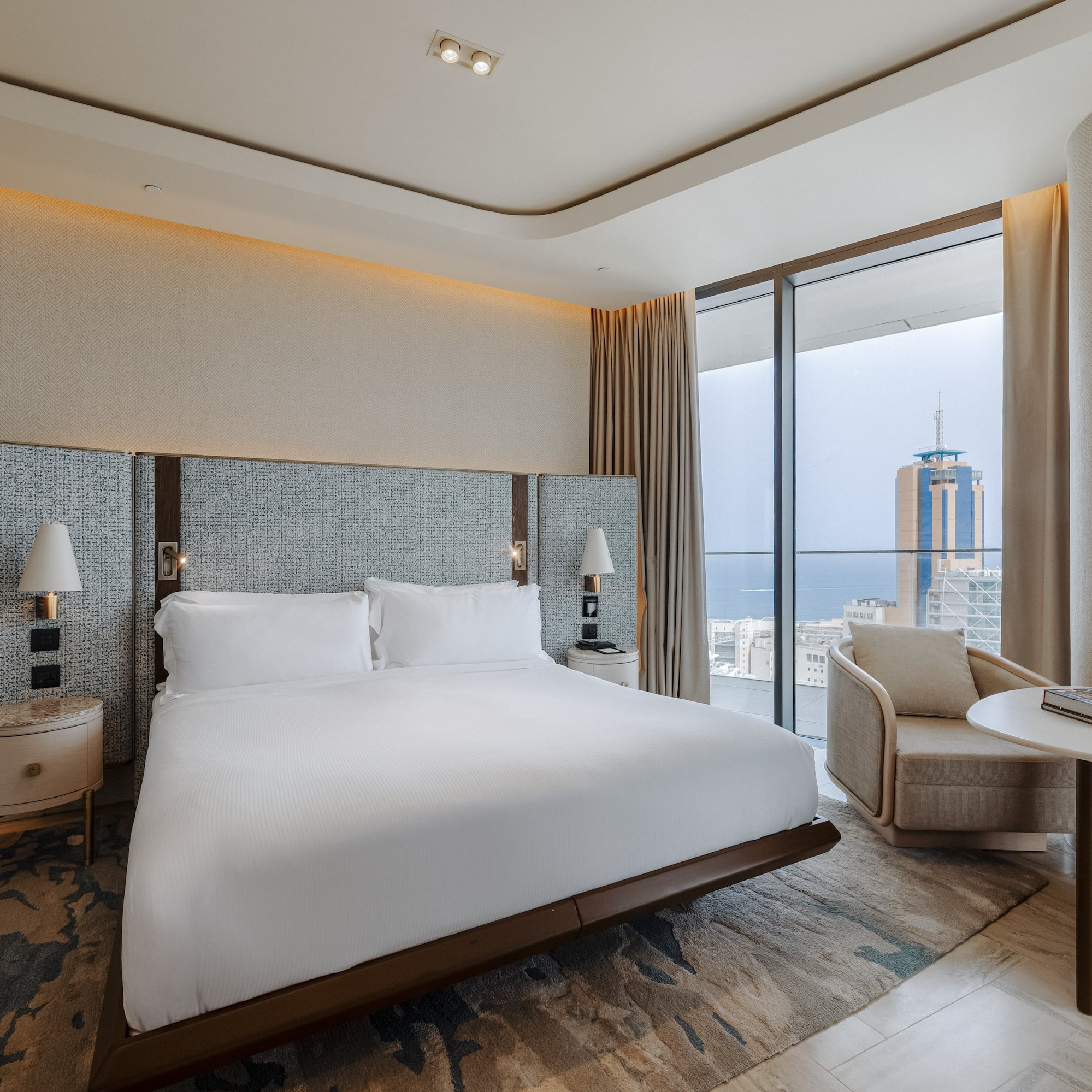 Luxury hotel bedroom with king bed, modern decor, and stunning city/sea view.