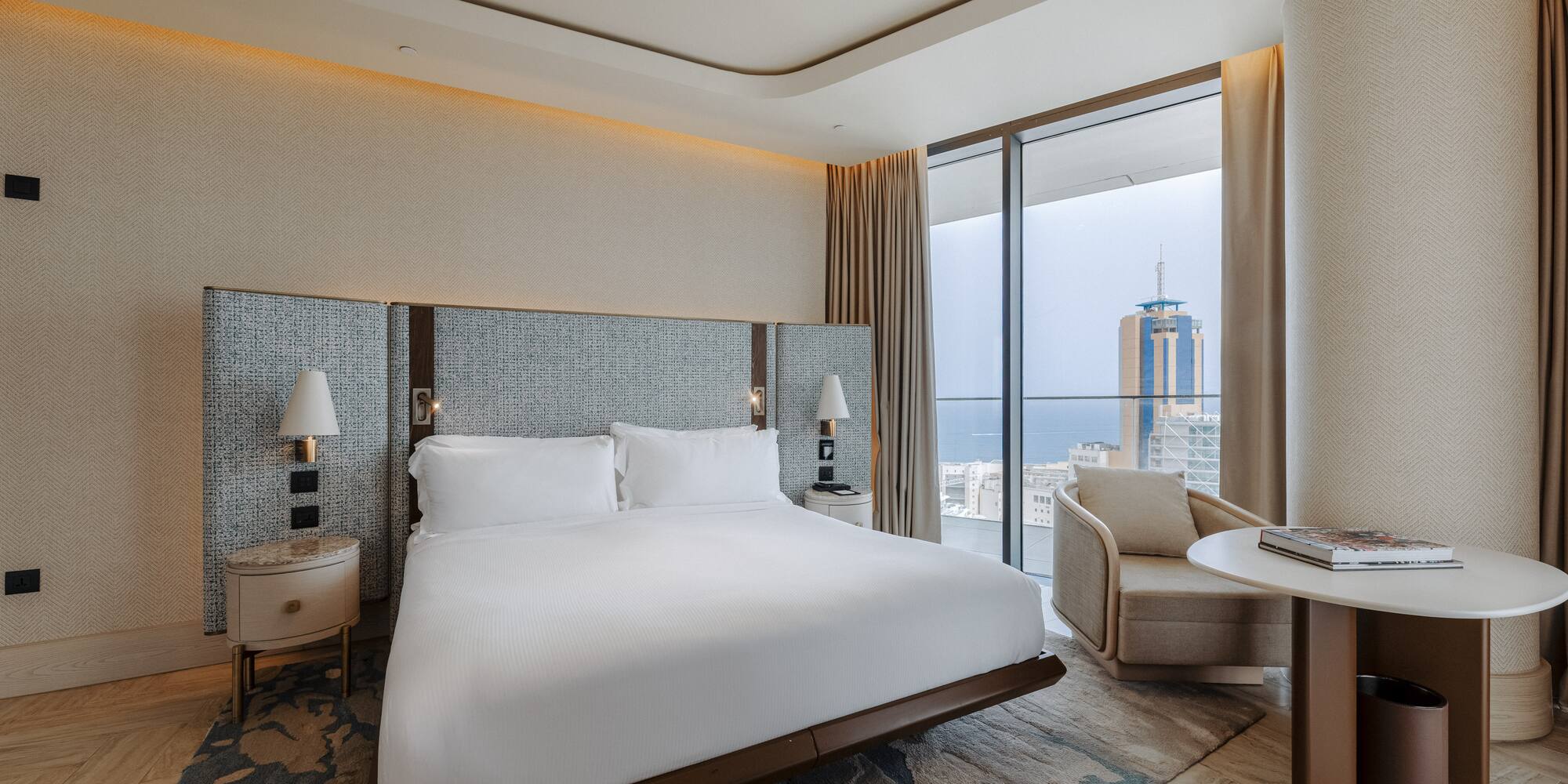 Luxury hotel bedroom with king bed, modern decor, and stunning city/sea view.