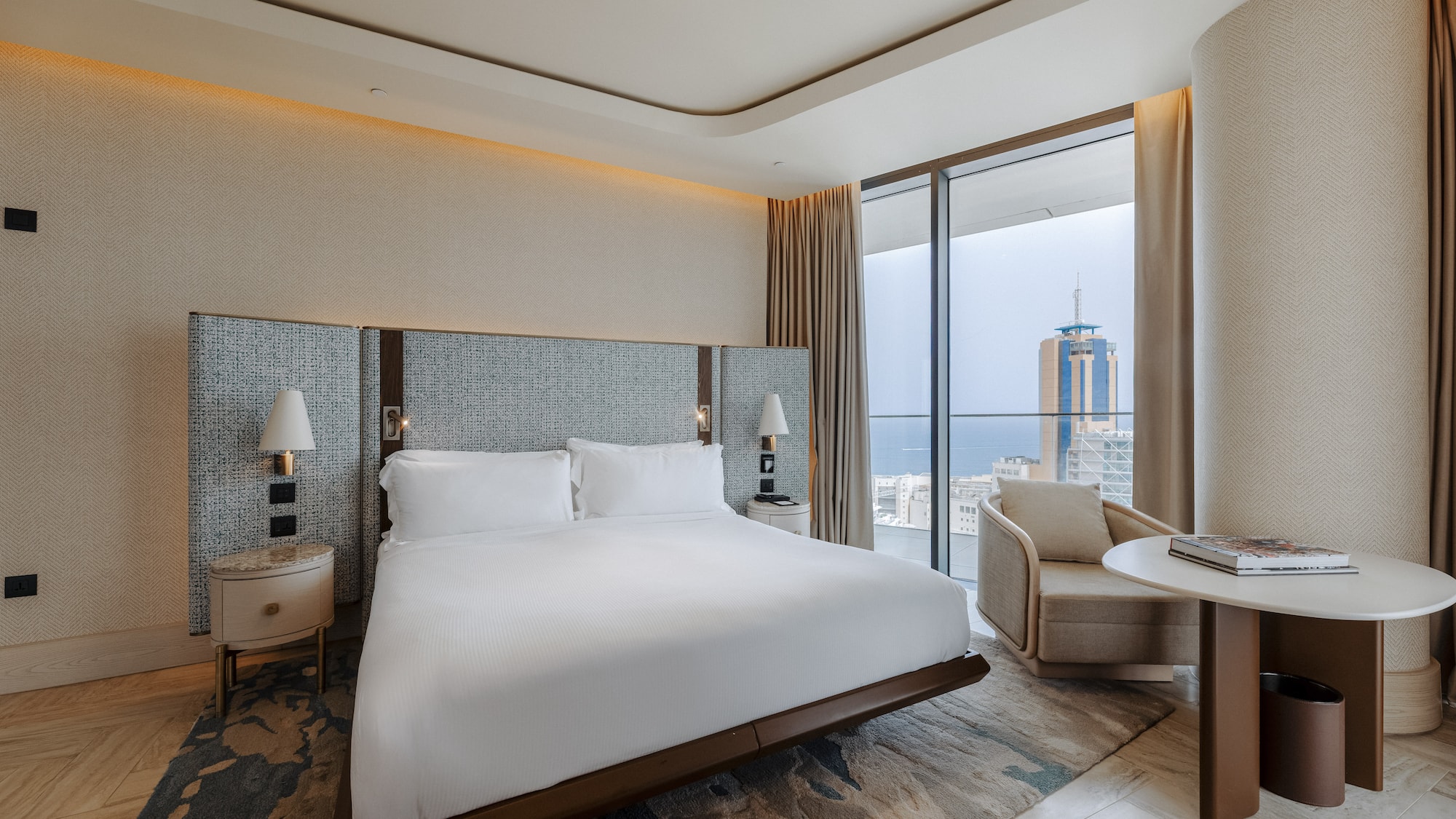 Luxury hotel bedroom with king bed, modern decor, and stunning city/sea view.
