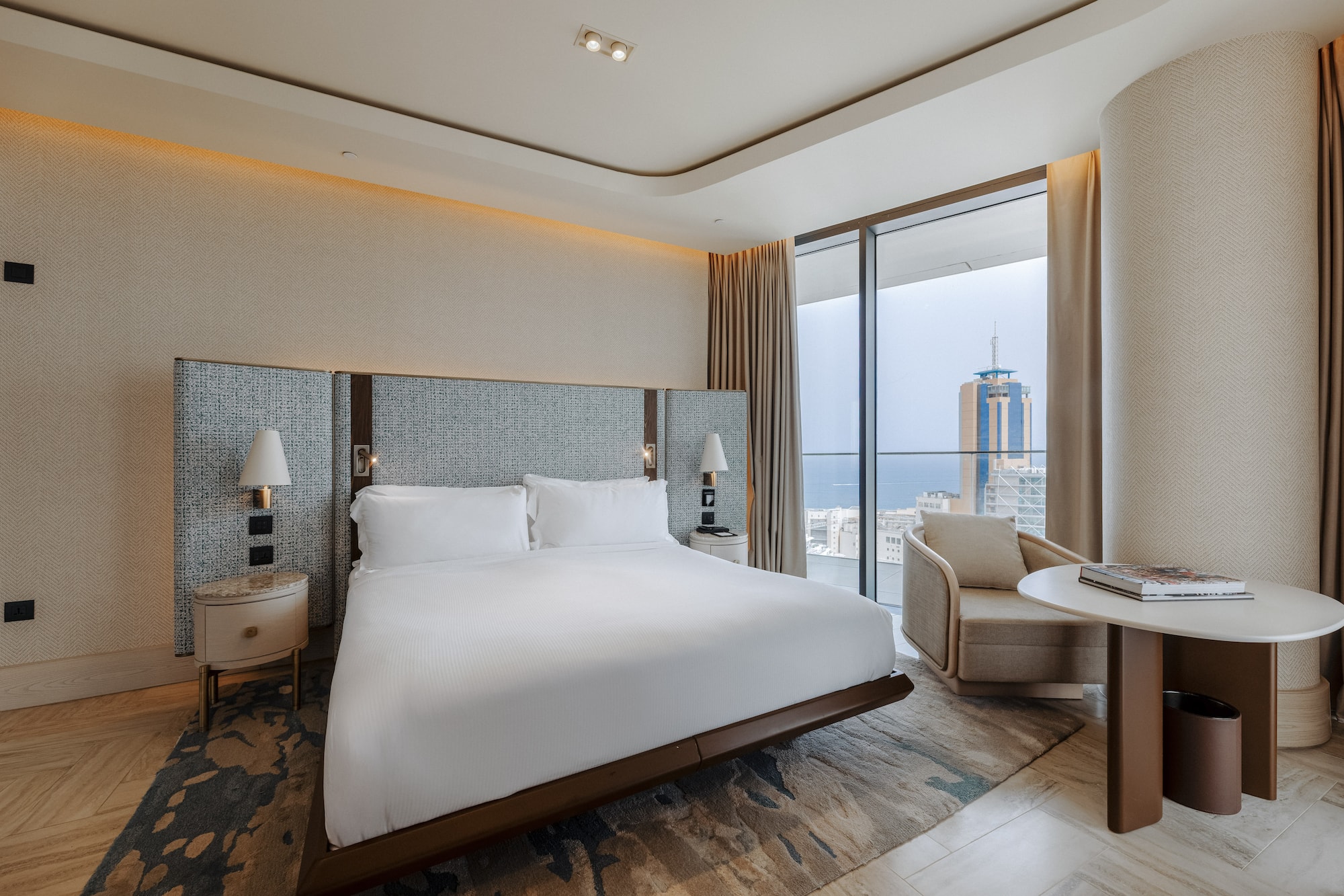 Luxury hotel bedroom with king bed, modern decor, and stunning city/sea view.