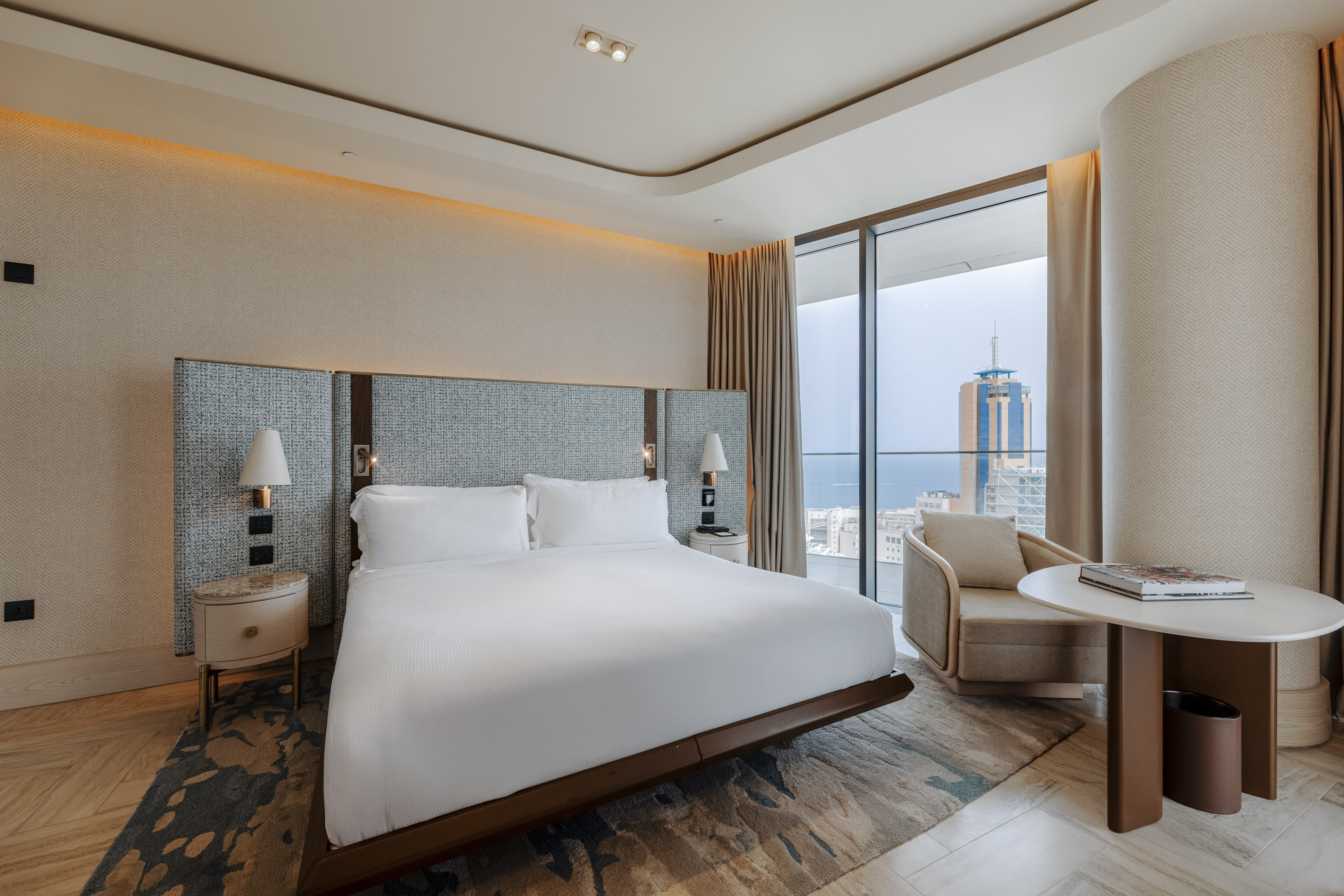 Luxury hotel bedroom with king bed, modern decor, and stunning city/sea view.