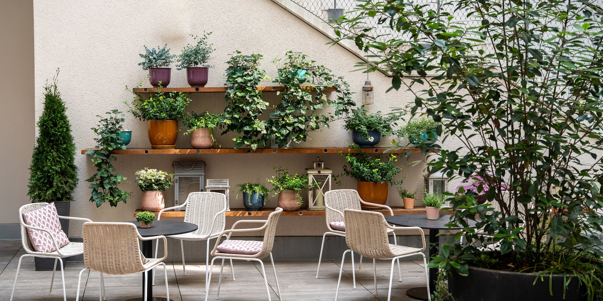 a patio with chairs and tables and potted plants