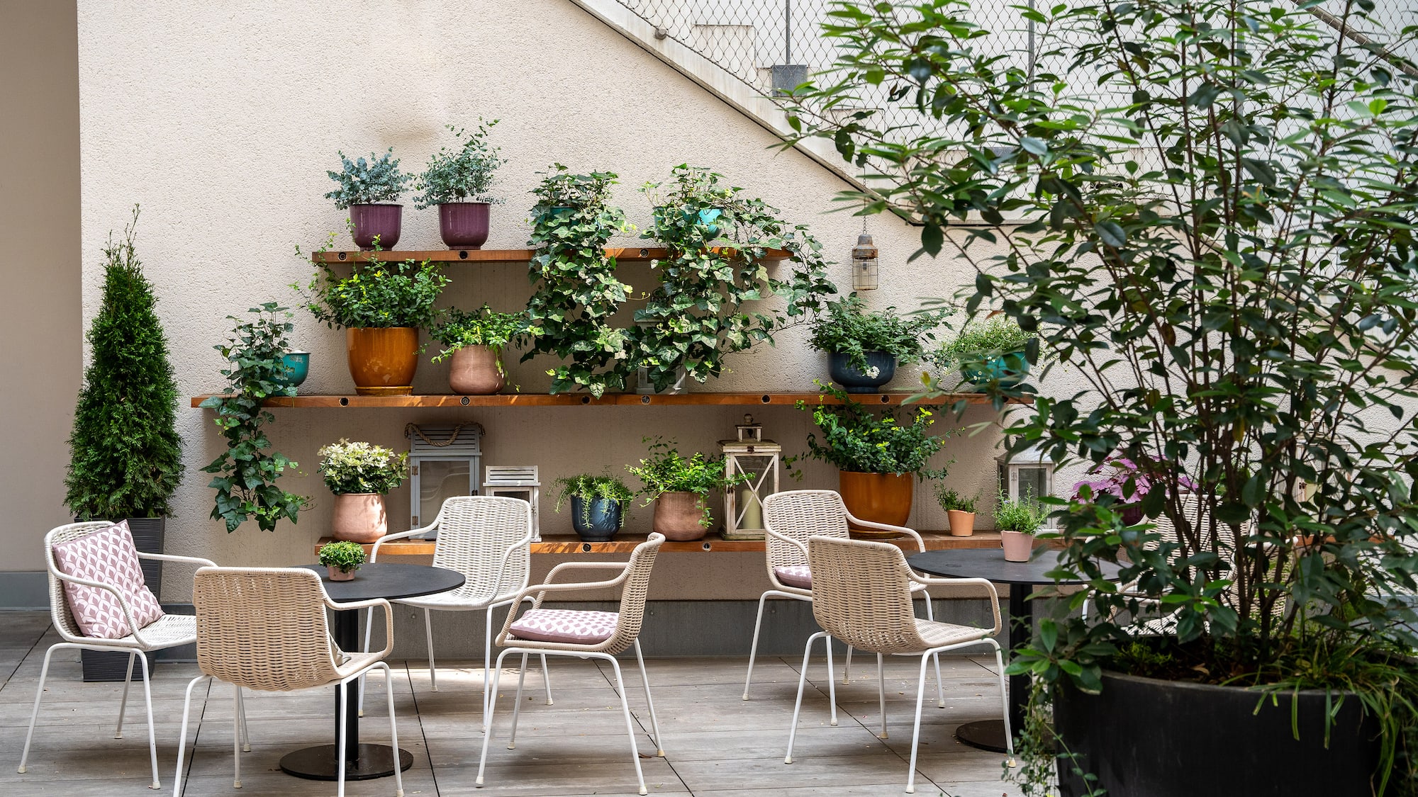 a patio with chairs and tables and potted plants