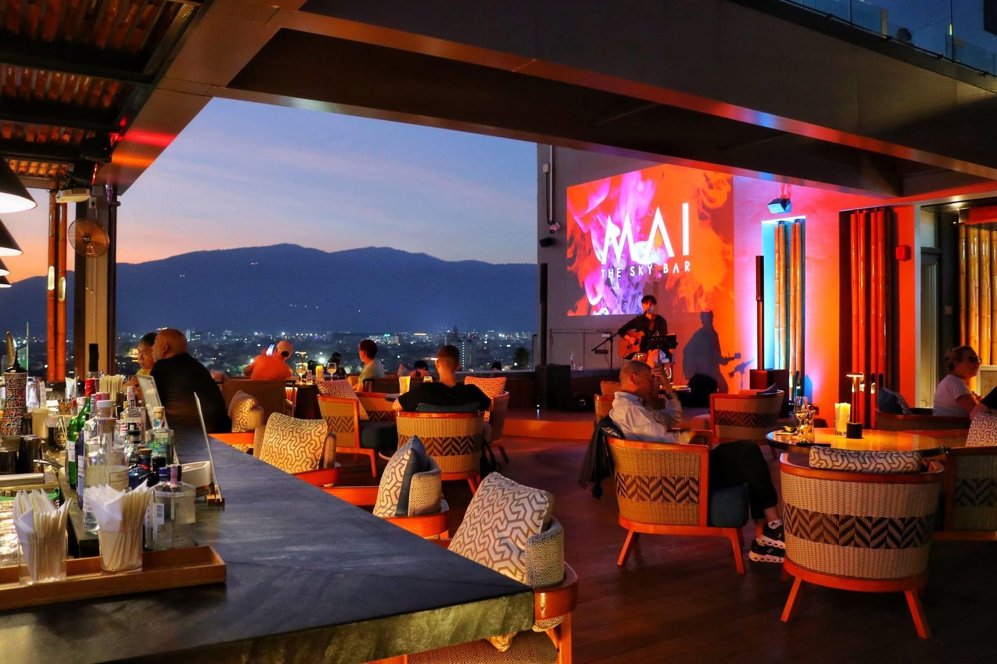MAI THE SKY BAR rooftop lounge at sunset with live music and city views.