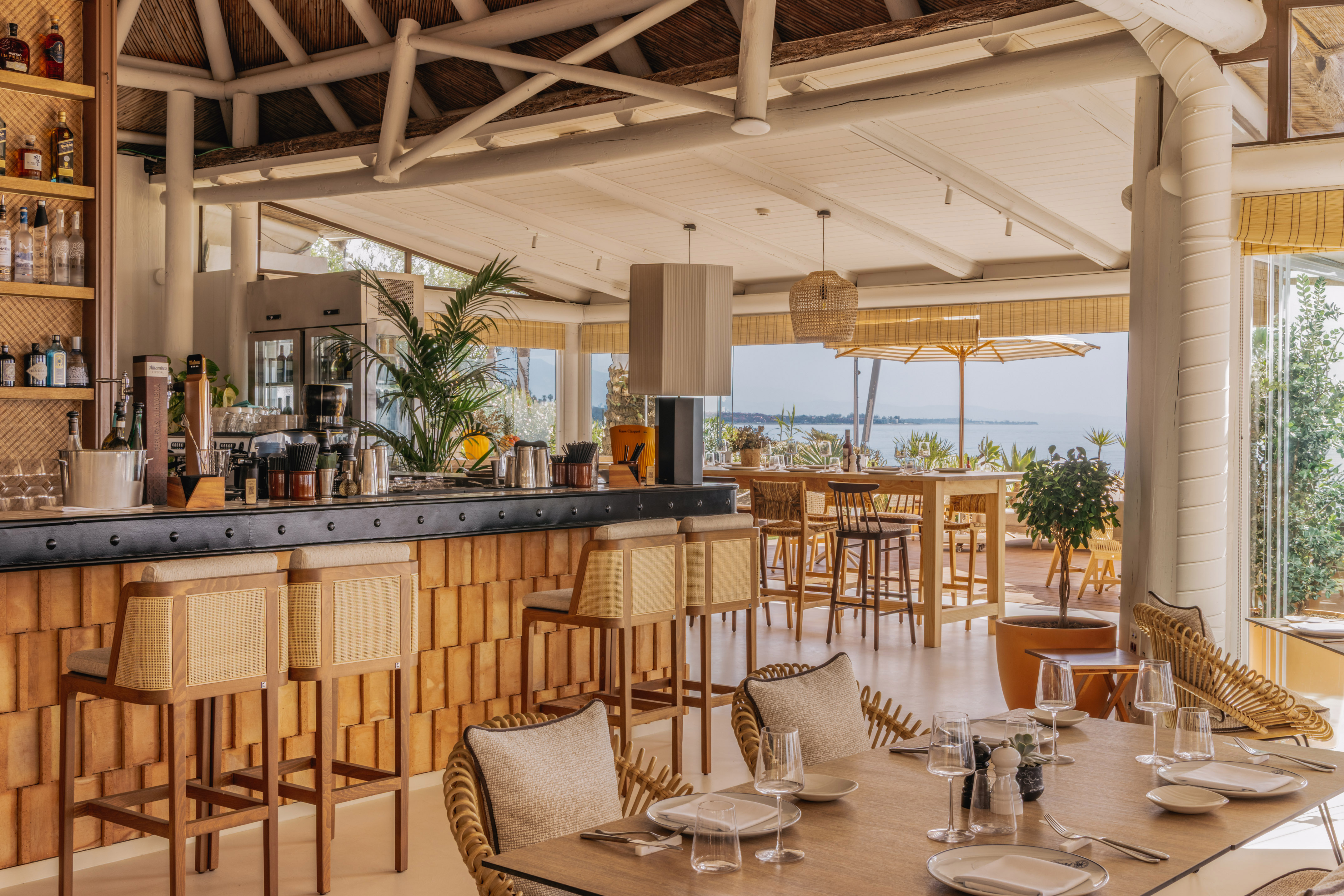 Waterfront restaurant and bar with rattan furniture and lake view.