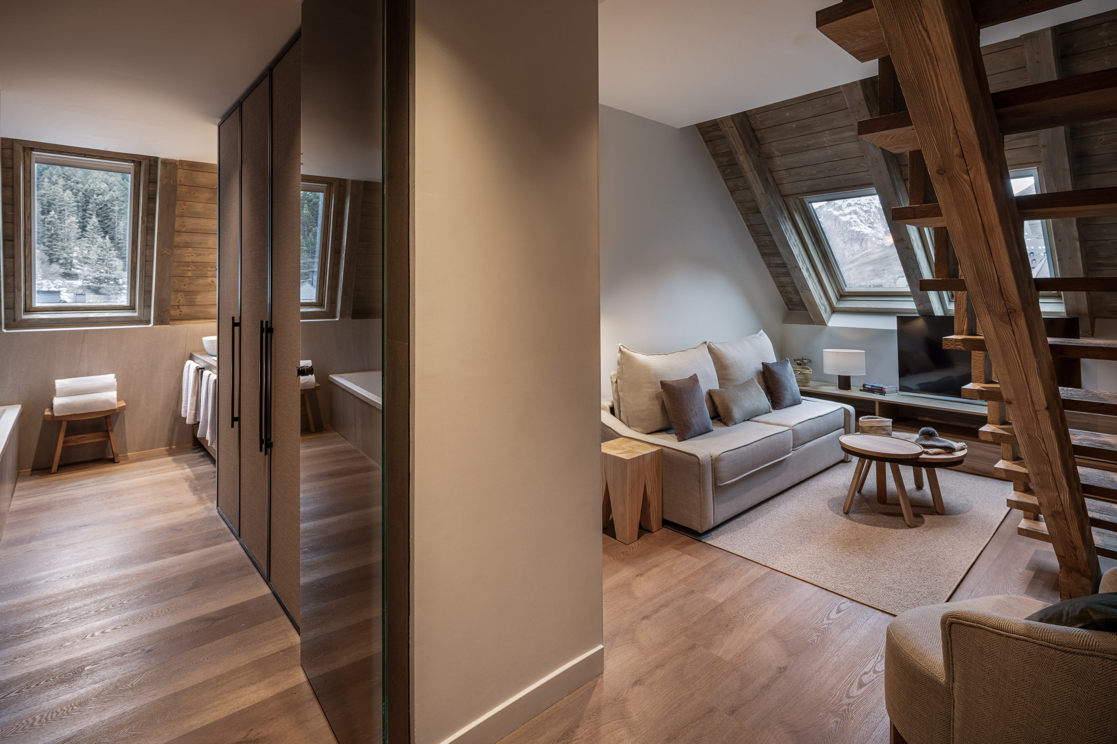 Modern chalet apartment living area with mountain view, wood interior, and bath.