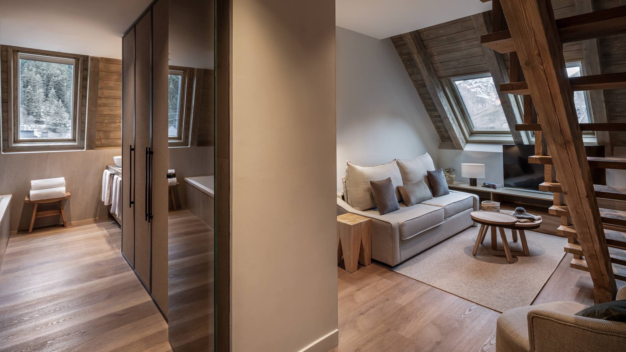 Modern chalet apartment living area with mountain view, wood interior, and bath.