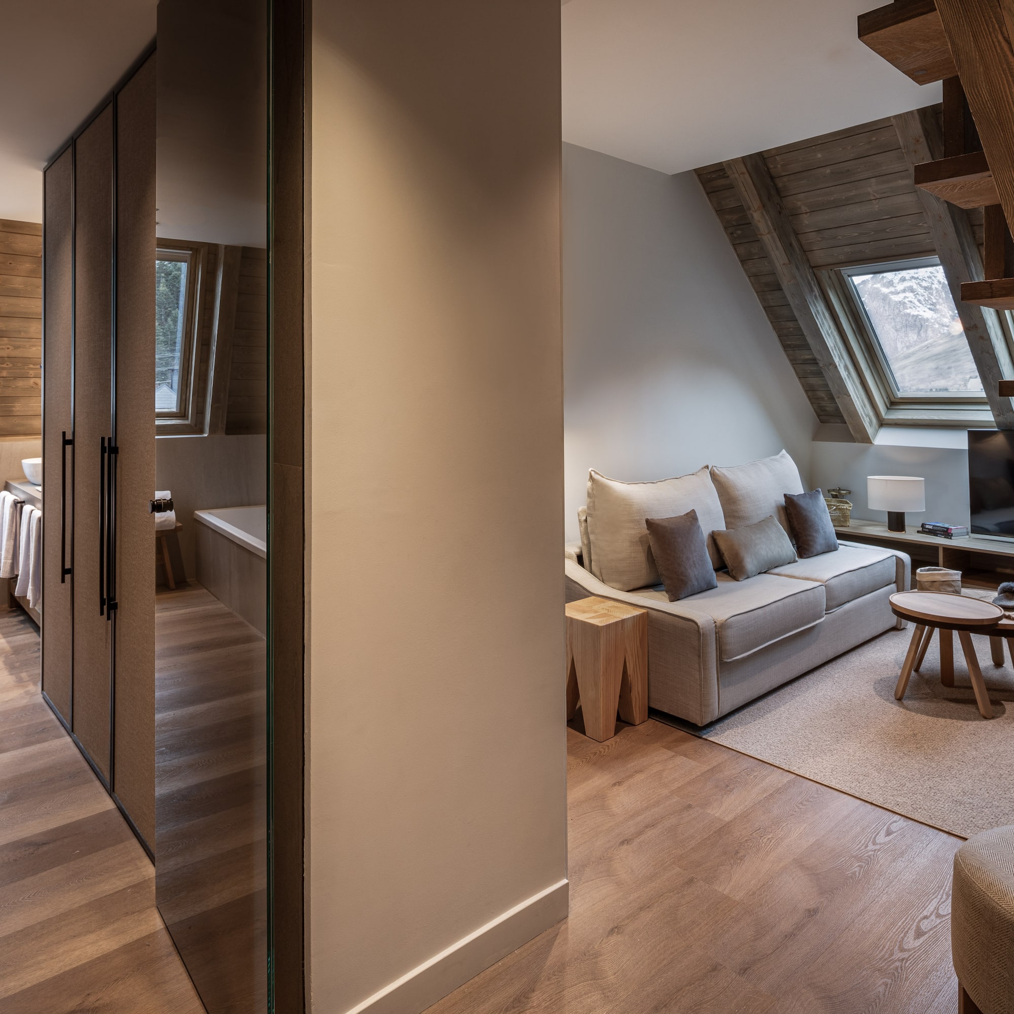 Modern chalet apartment living area with mountain view, wood interior, and bath.