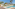 Resort swimming pool with sunbeds, thatched umbrellas, and palm trees.