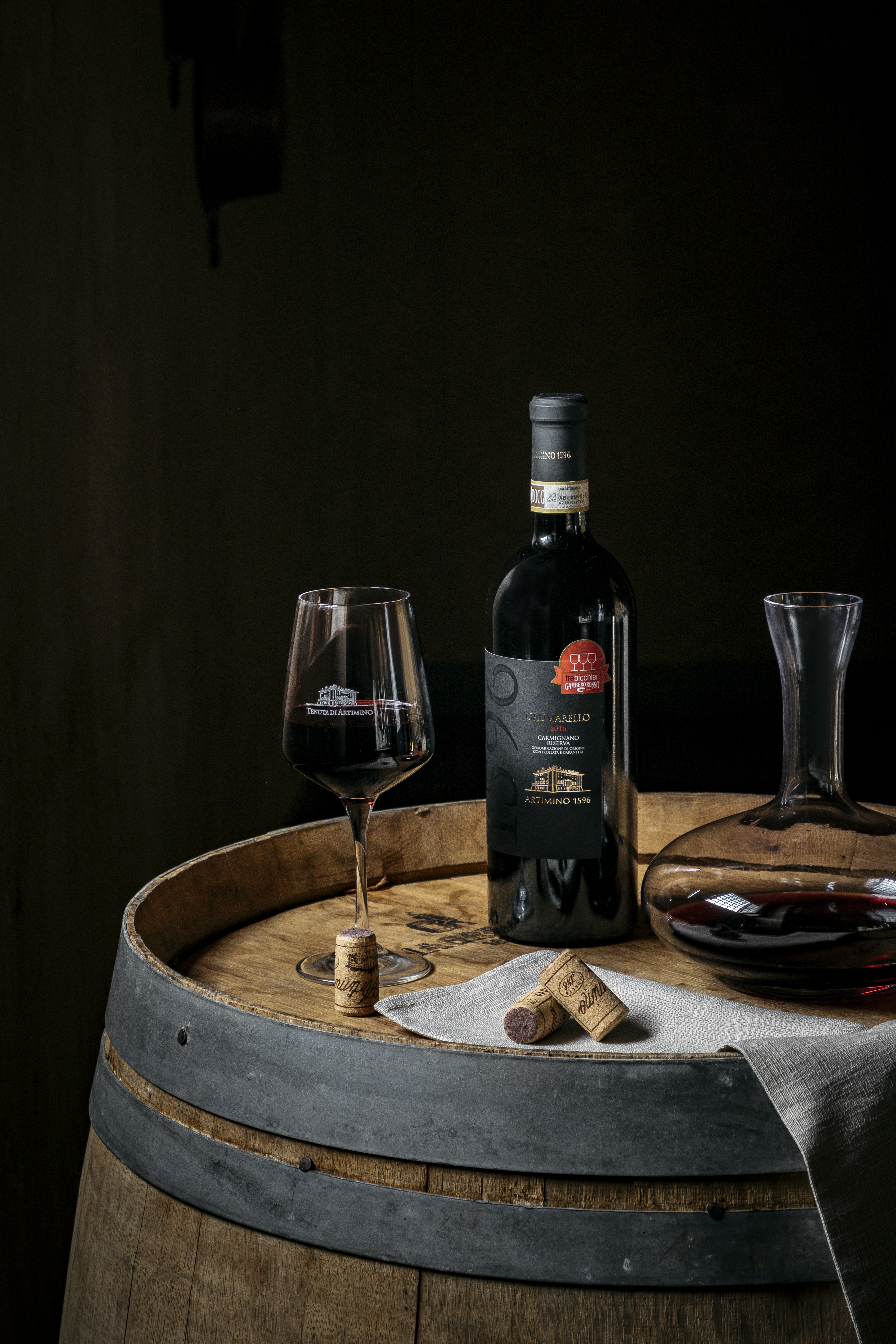 a bottle of wine and a glass of wine on a barrel