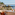 a table with glasses and a chair on a balcony overlooking the ocean