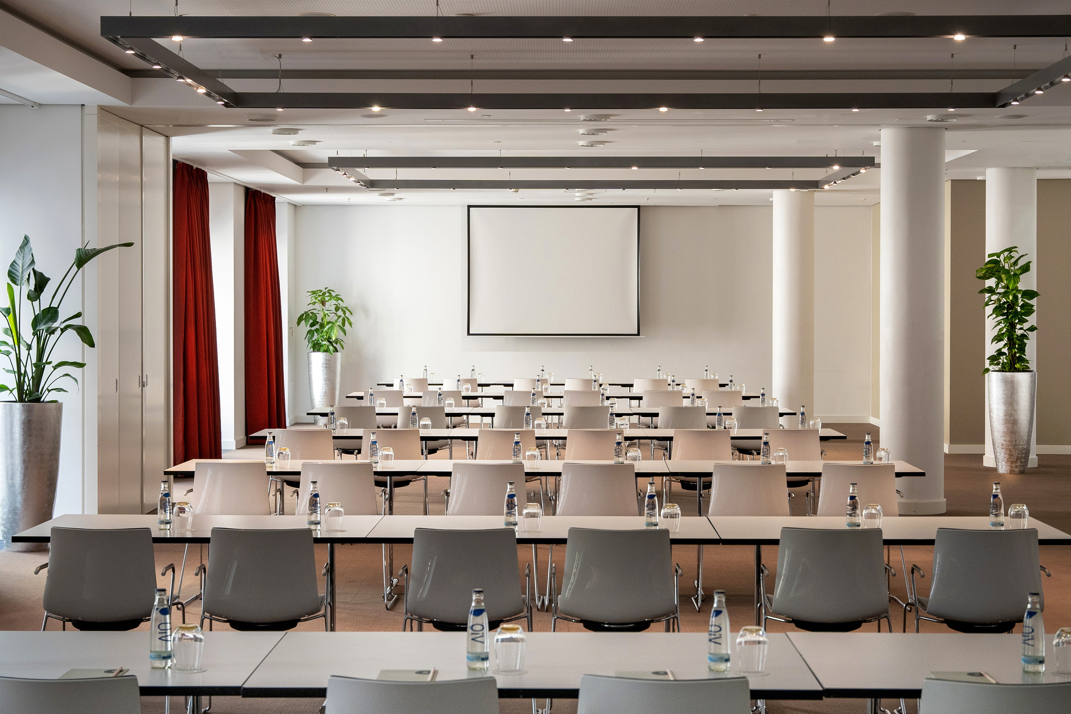 Modern conference room, classroom seating, projector screen, red accents.