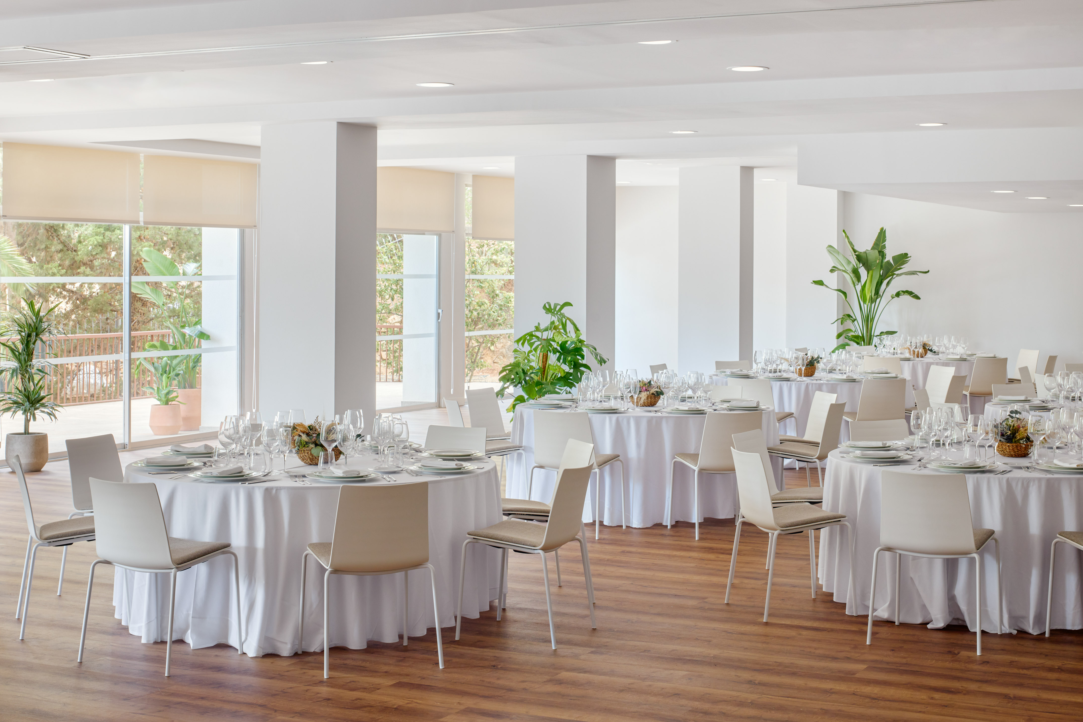 Bright event hall with round dining tables, modern chairs, and natural light.