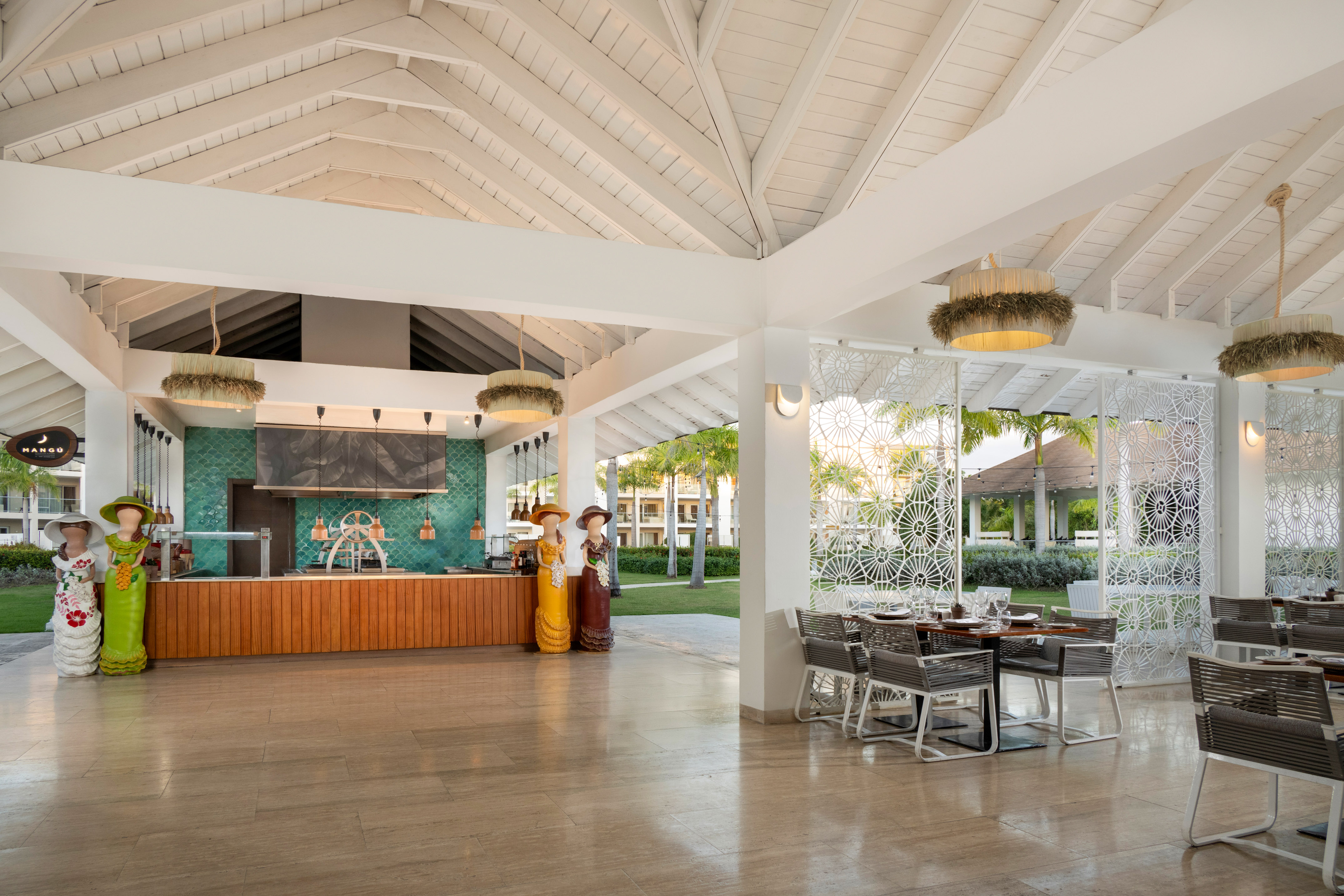 Modern open-air resort restaurant with vaulted ceiling, bar, and tropical dining.