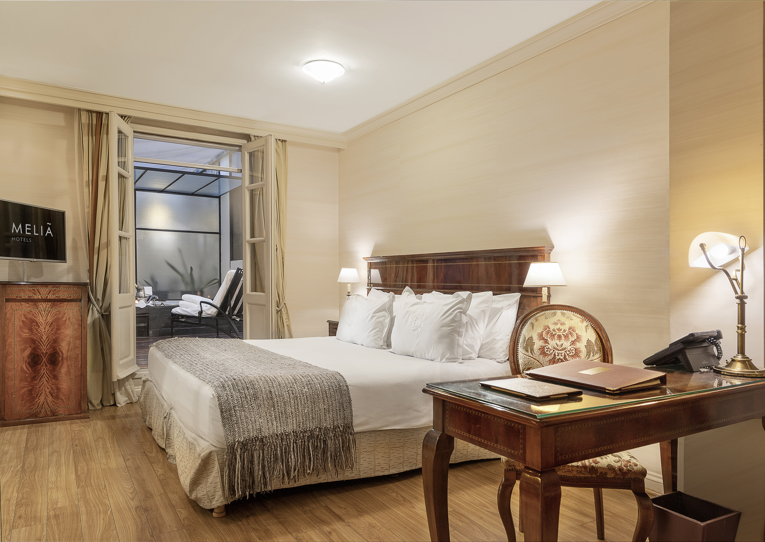 Meliã Hotels bedroom with large bed, desk, and private balcony view.