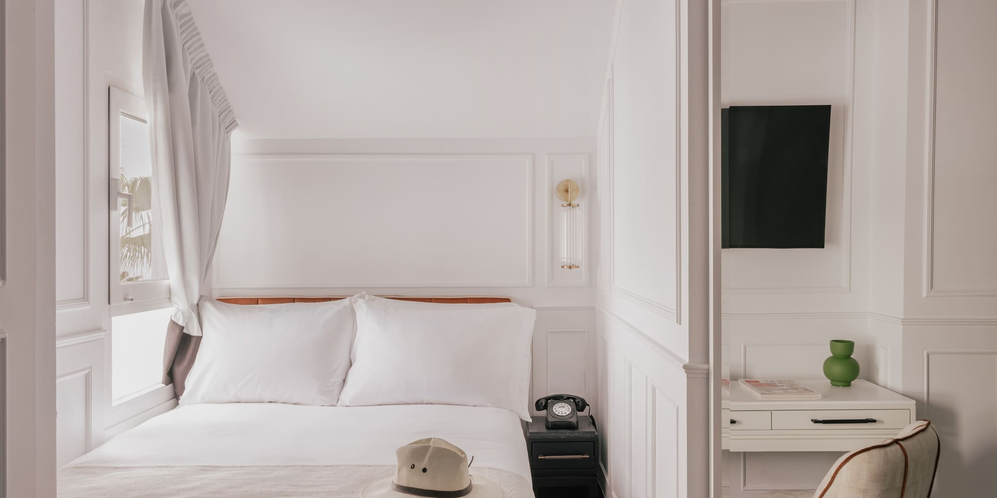 Boutique hotel room with white bed, vintage phone, desk, black trim.
