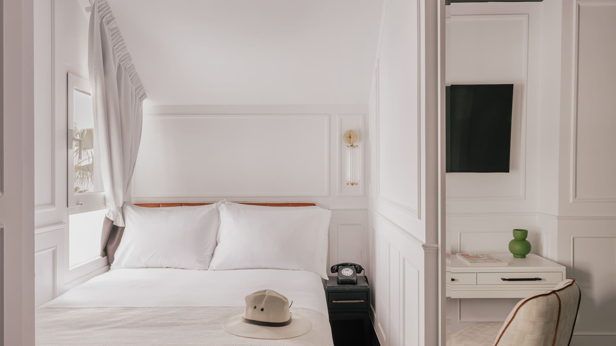 Elegant black and white hotel room with bed, desk, and vintage phone.
