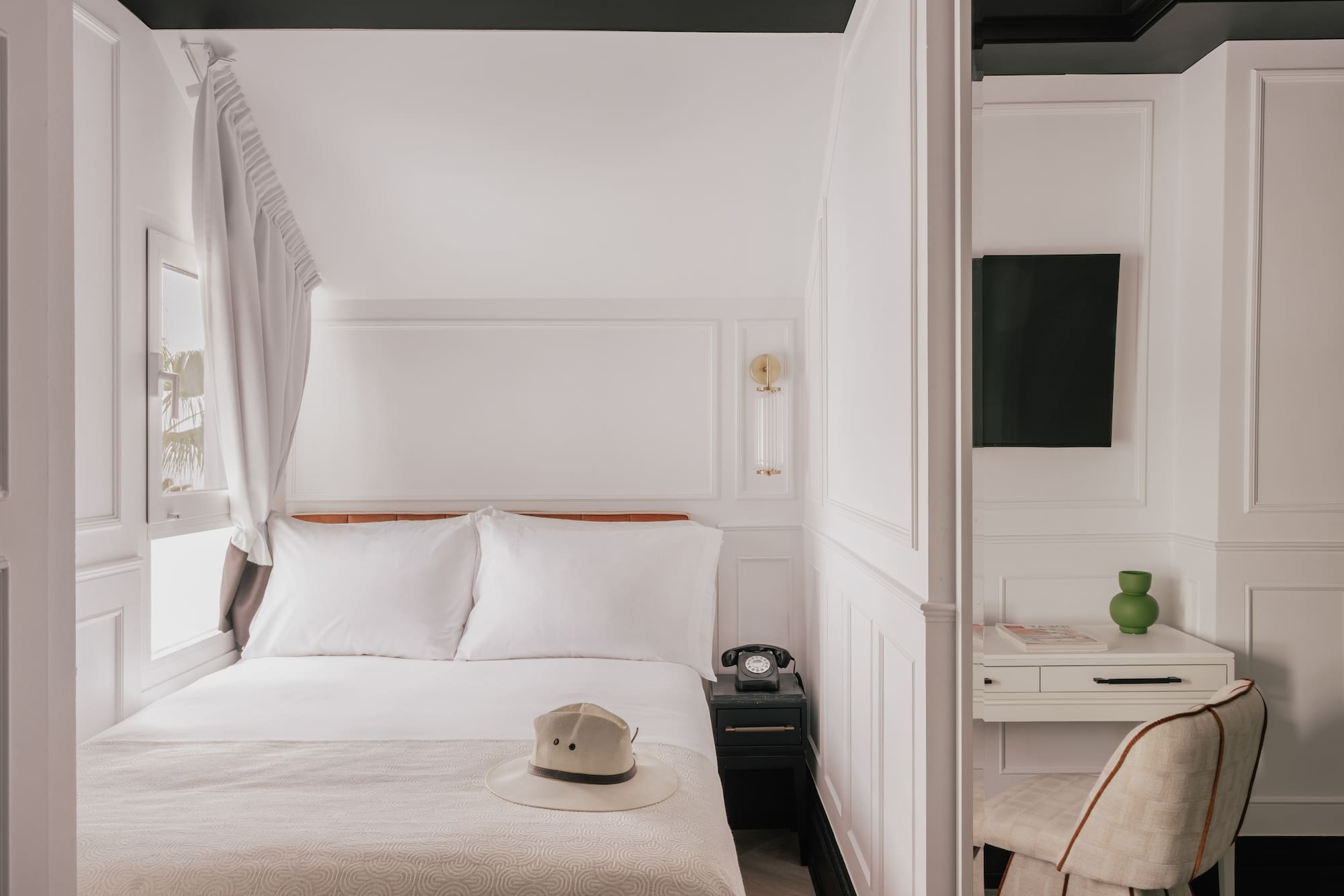 Boutique hotel room with white bed, vintage phone, desk, black trim.