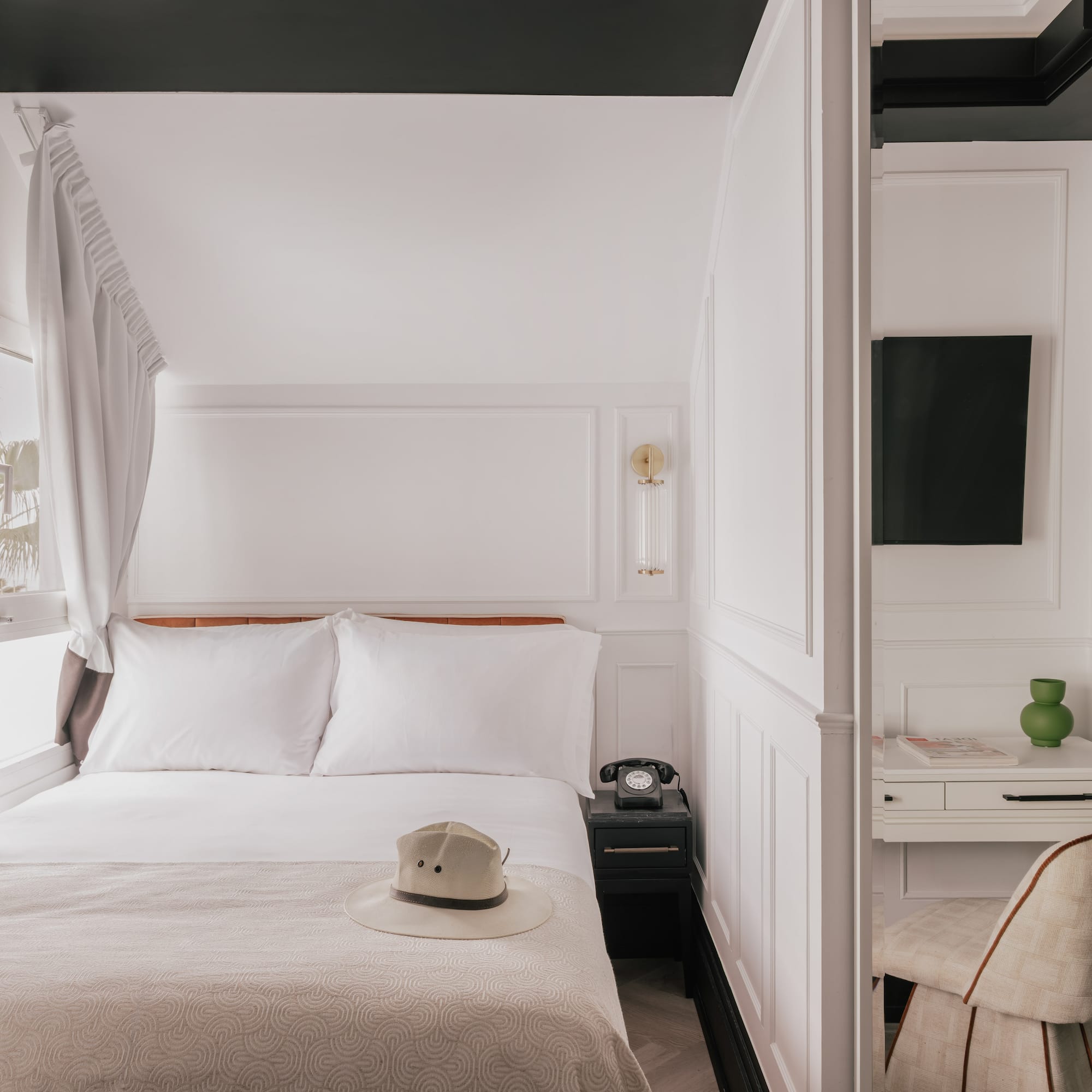 Boutique hotel room with white bed, vintage phone, desk, black trim.