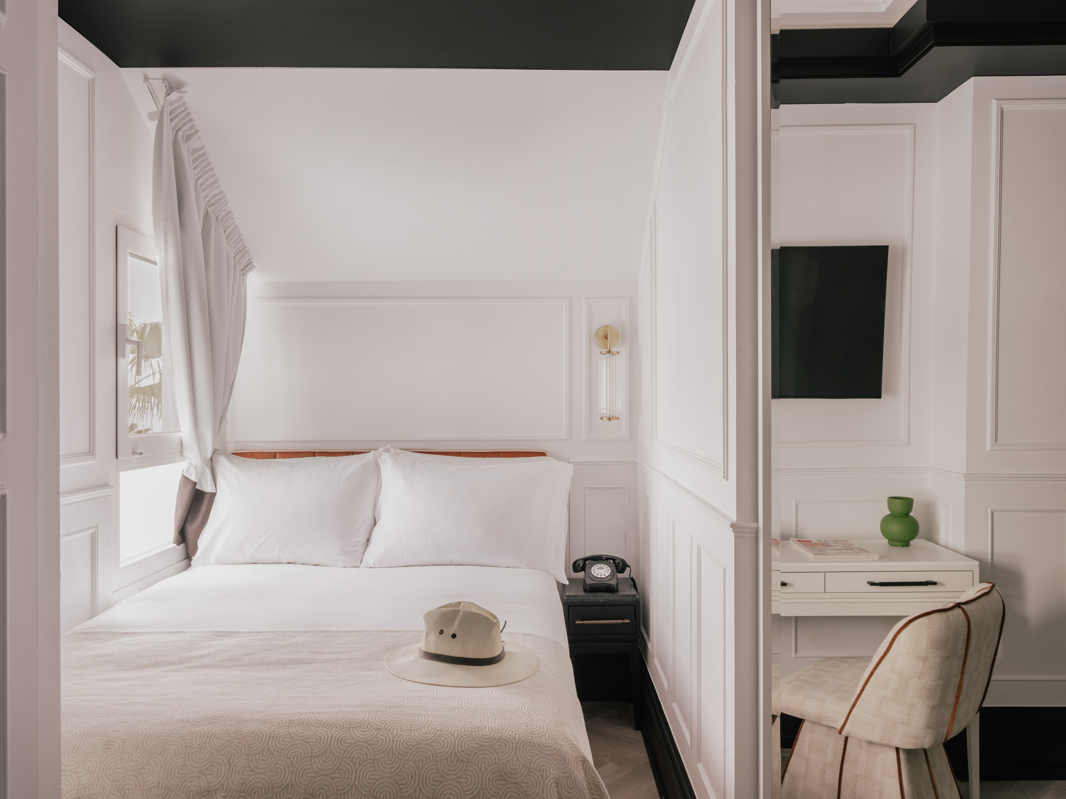 Boutique hotel room with white bed, vintage phone, desk, black trim.