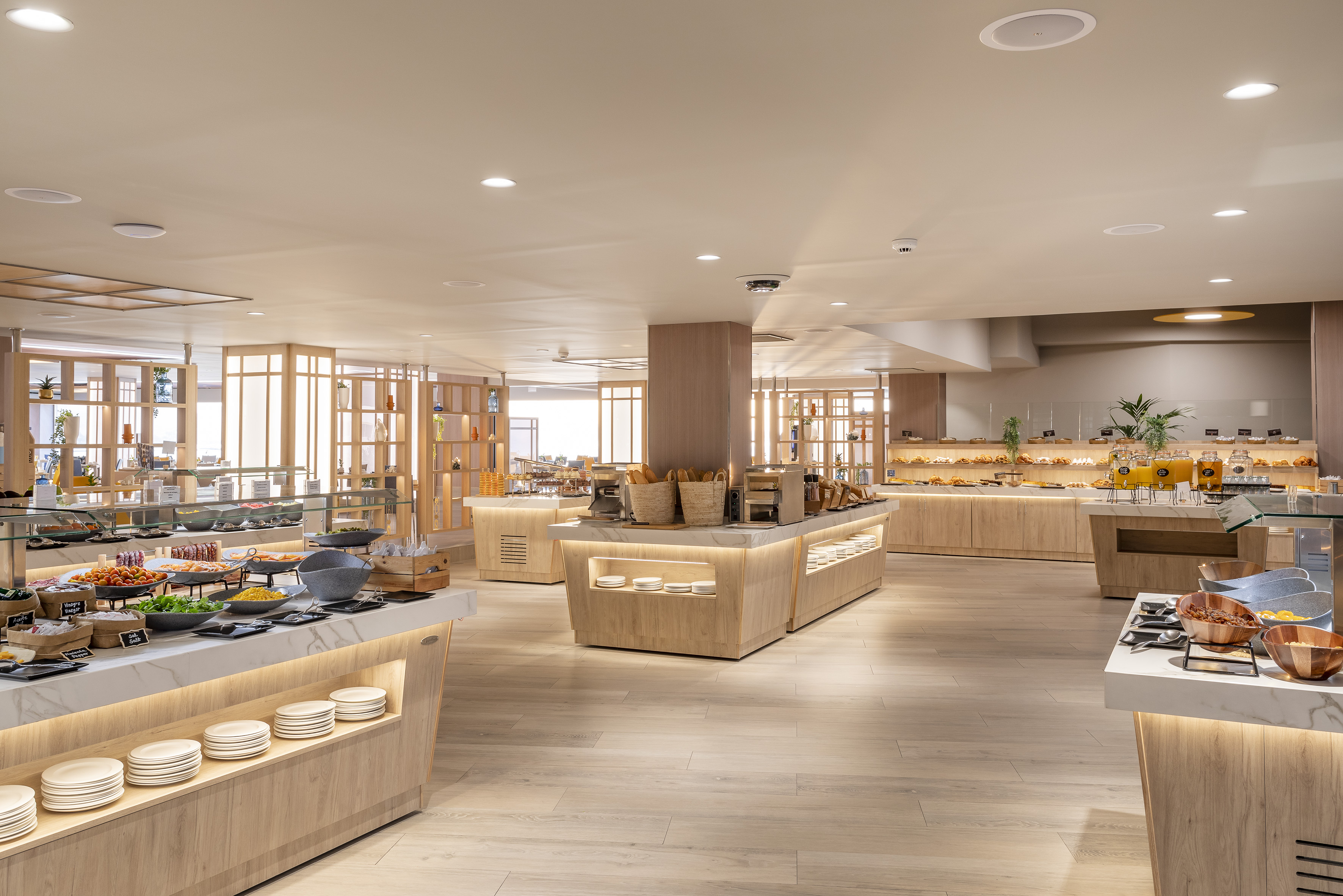 Modern breakfast buffet with various food stations, fresh pastries, and juices.