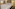 Modern hotel suite with large bed, sitting area, and bright open bathroom.