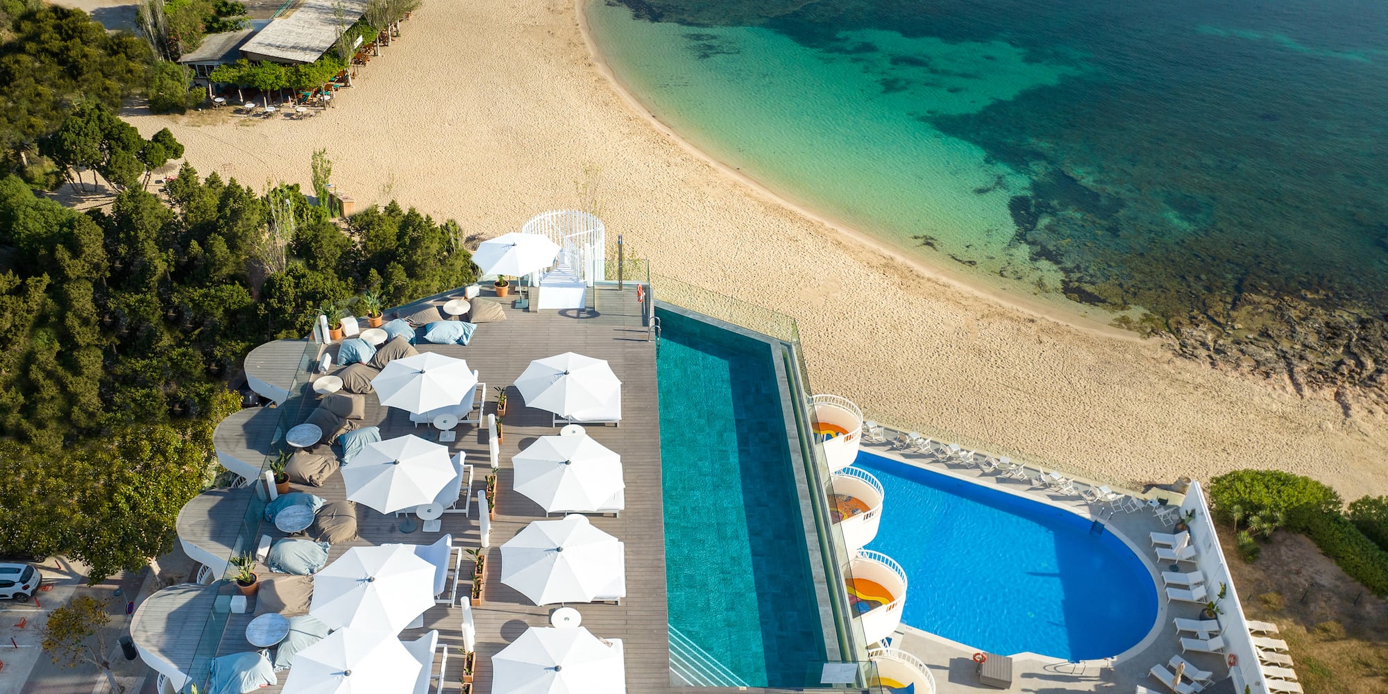 a pool and beach with umbrellas