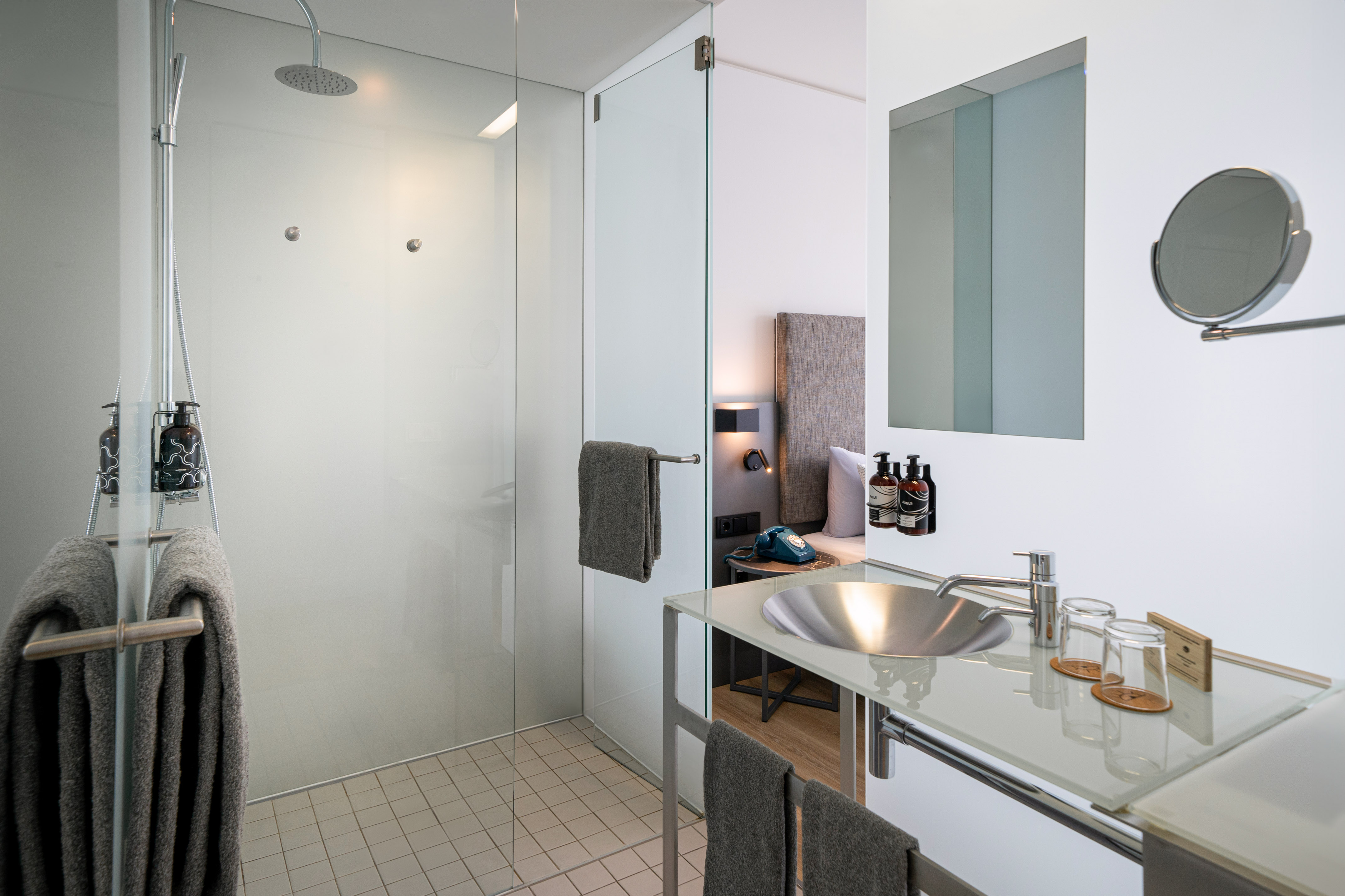 Modern hotel bathroom with glass shower, sleek sink, and minimalist design.