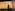 Málaga Cathedral tower and city skyline at sunset through reflective window.