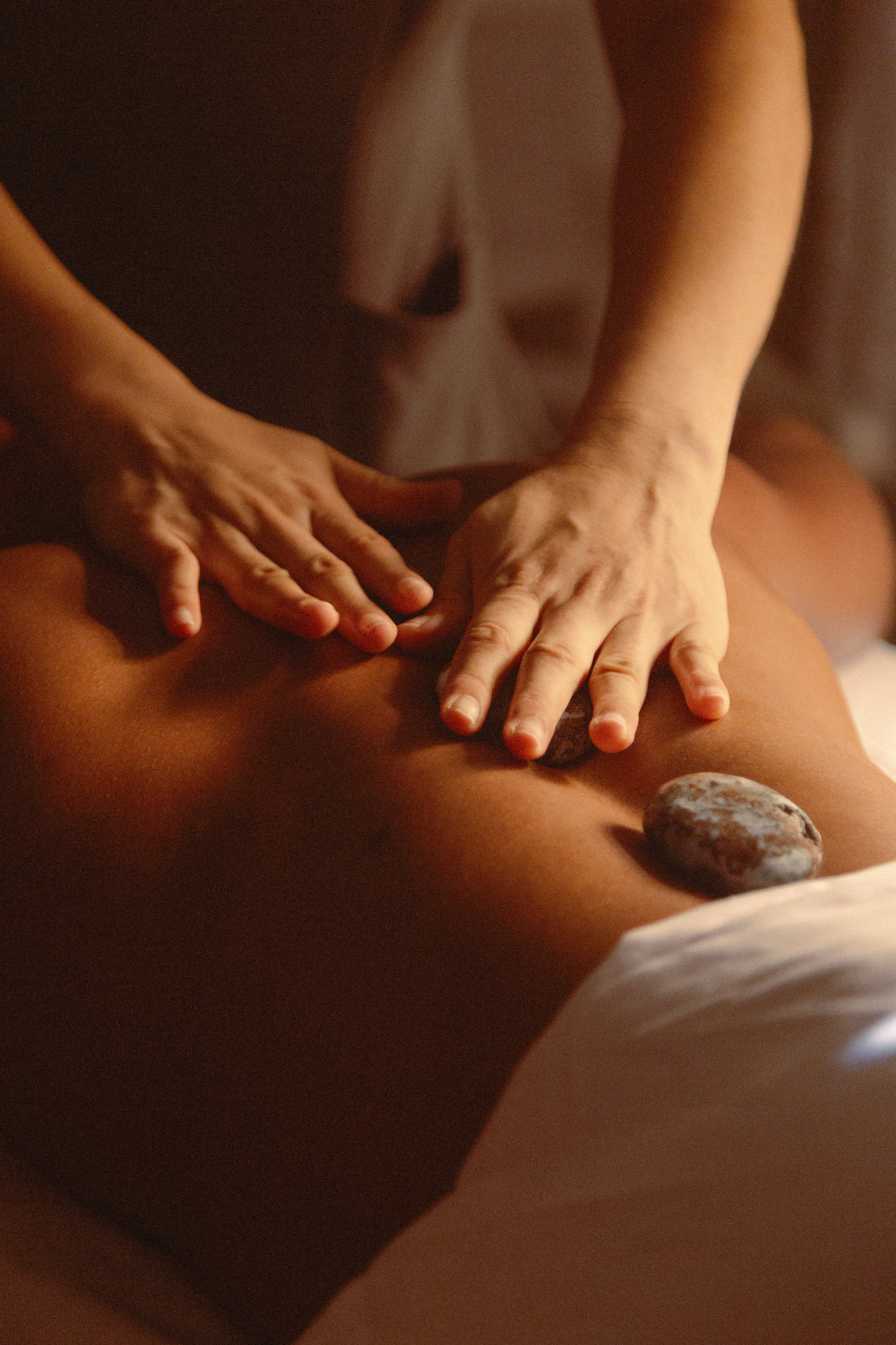 Therapist's hands performing hot stone back massage.