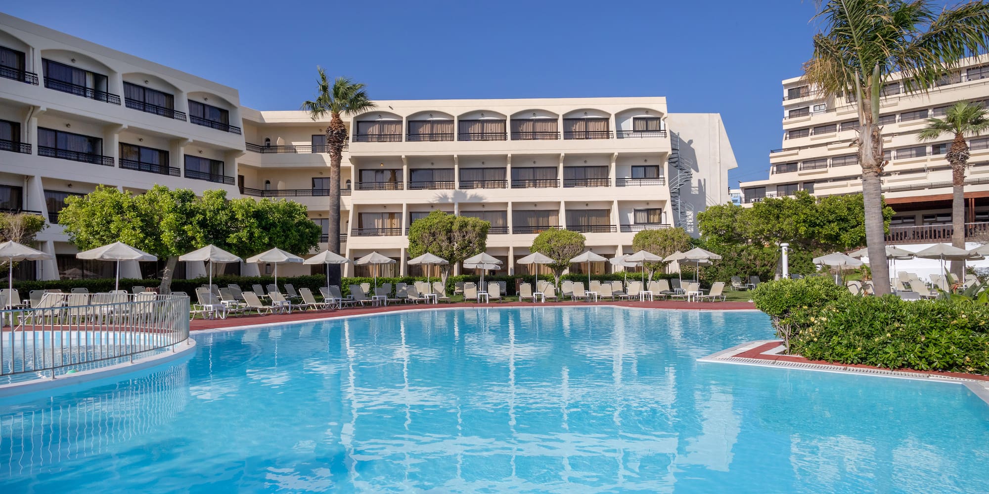 a swimming pool with trees and chairs in front of a building
