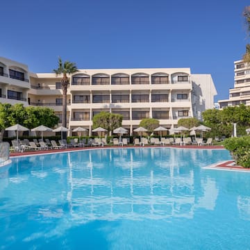 a swimming pool with trees and chairs in front of a building
