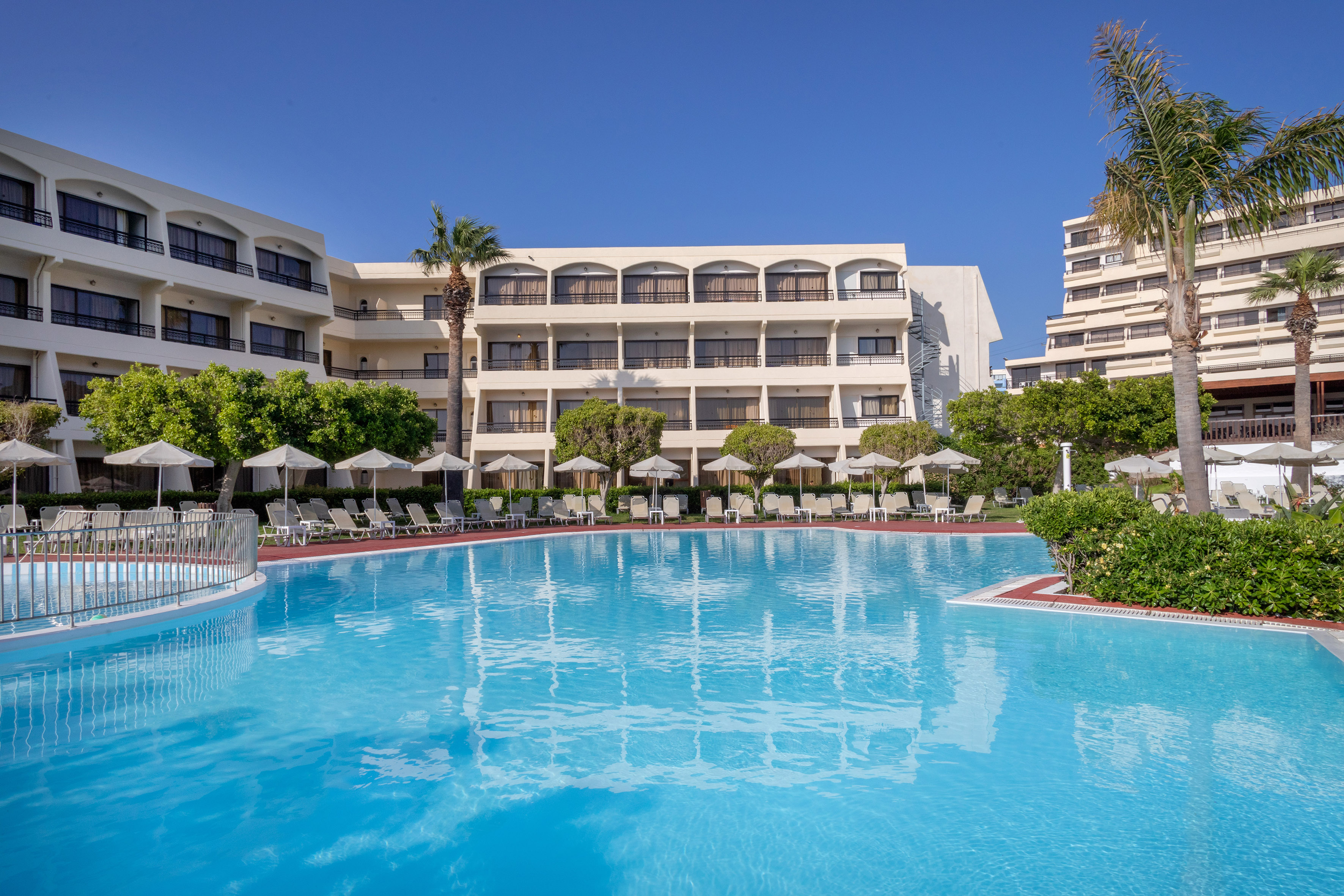 a swimming pool with trees and chairs in front of a building