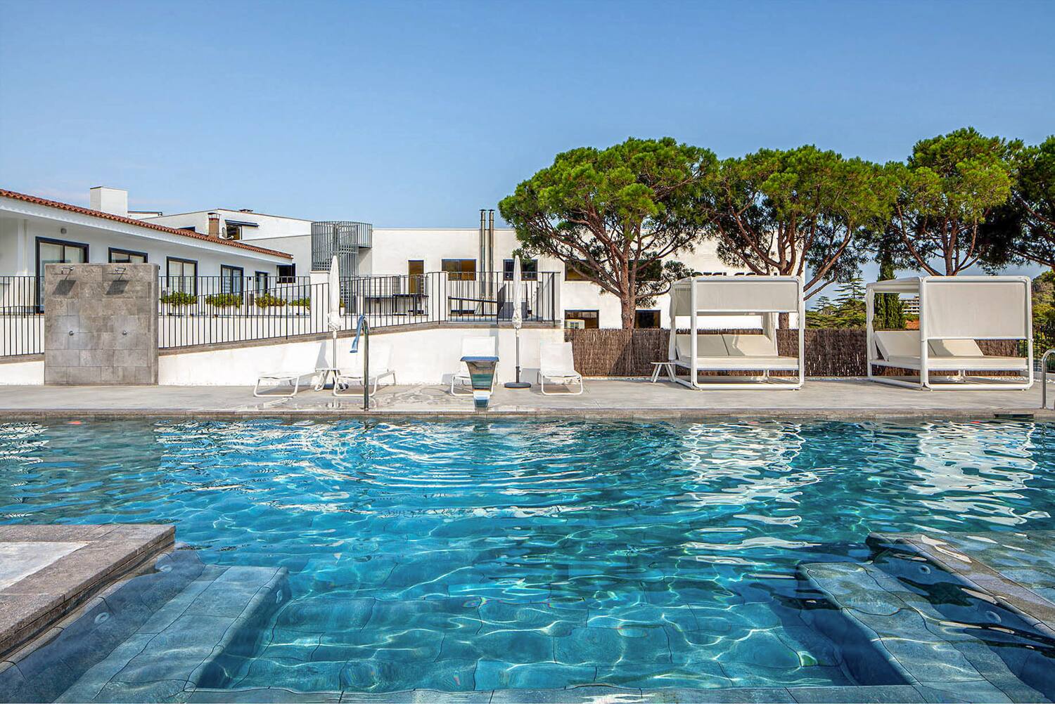 a swimming pool with a white building and trees