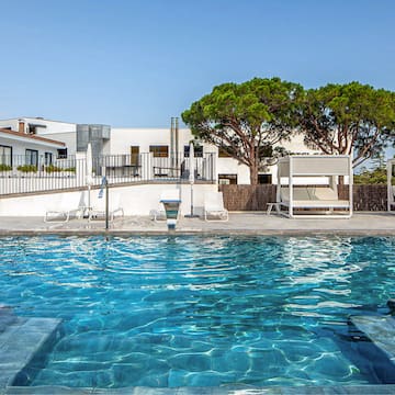 a swimming pool with a white building and trees