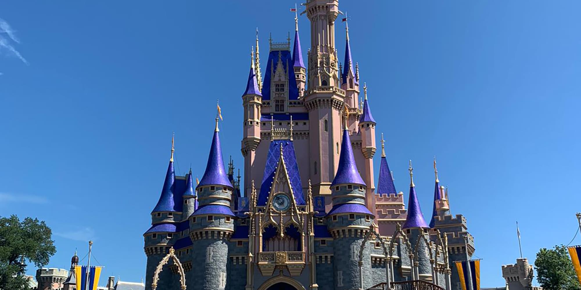 Cinderella Castle, Magic Kingdom, with blue and pink spires under clear sky.