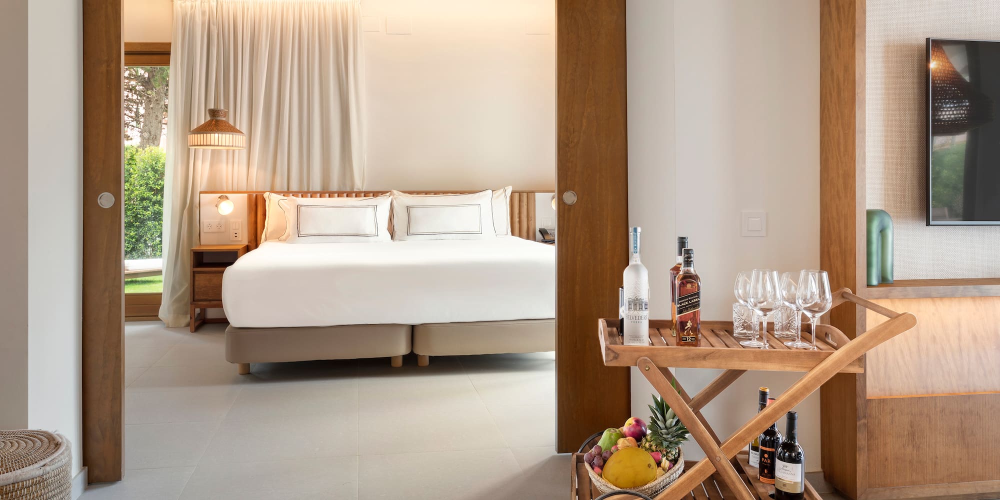 a room with a bed and a cart with wine bottles and glasses