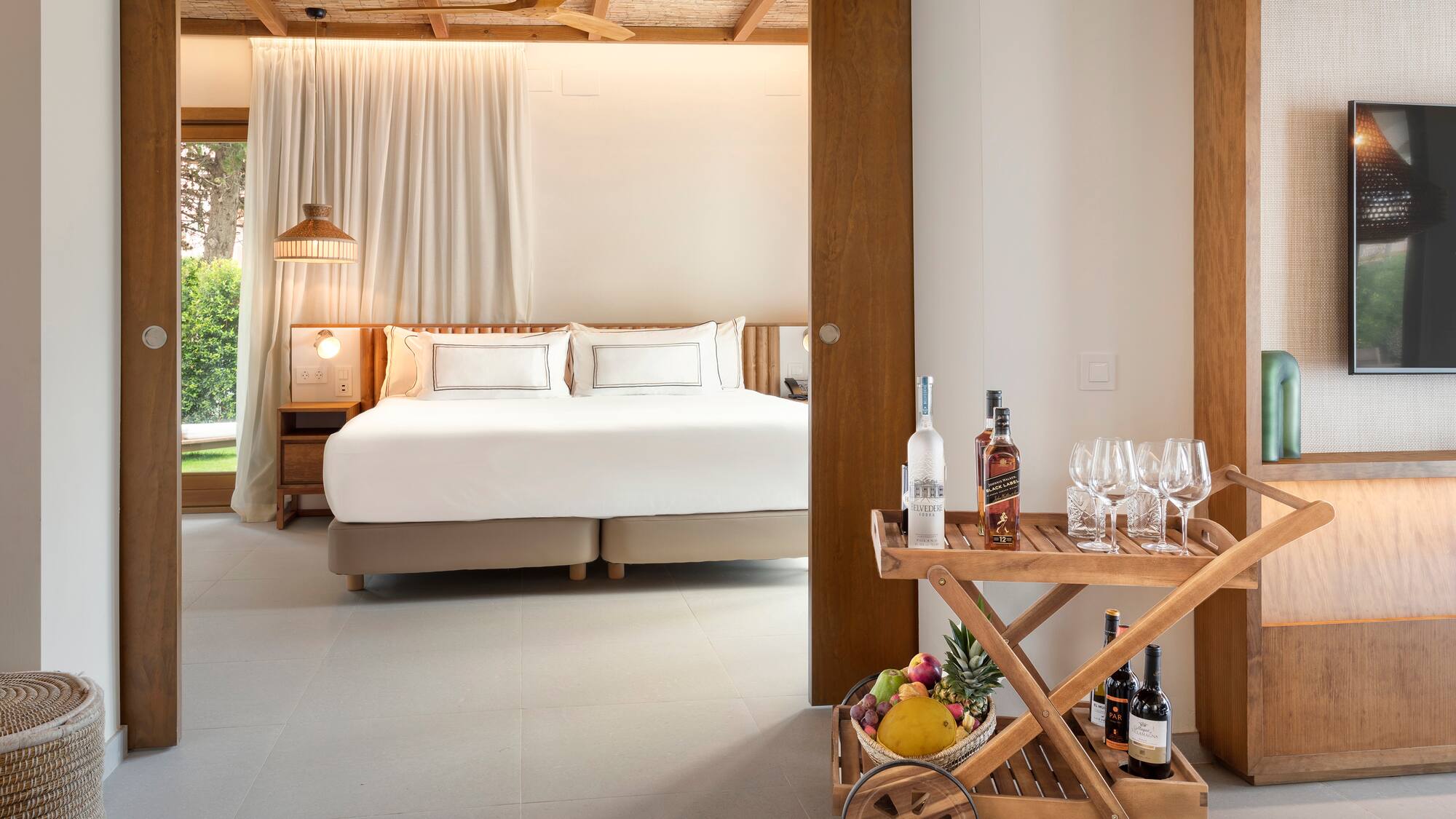 a room with a bed and a cart with wine bottles and glasses