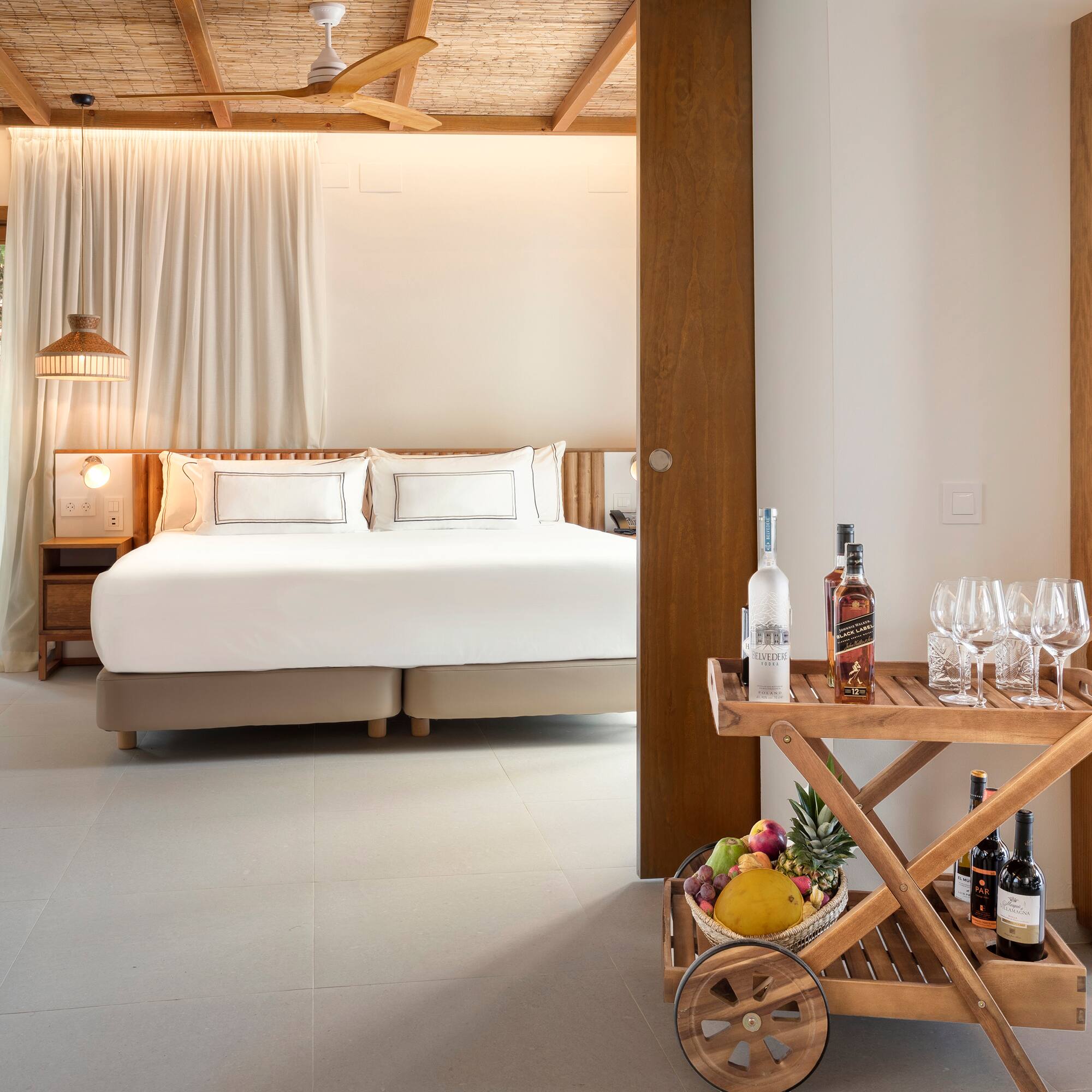 a room with a bed and a cart with wine bottles and glasses