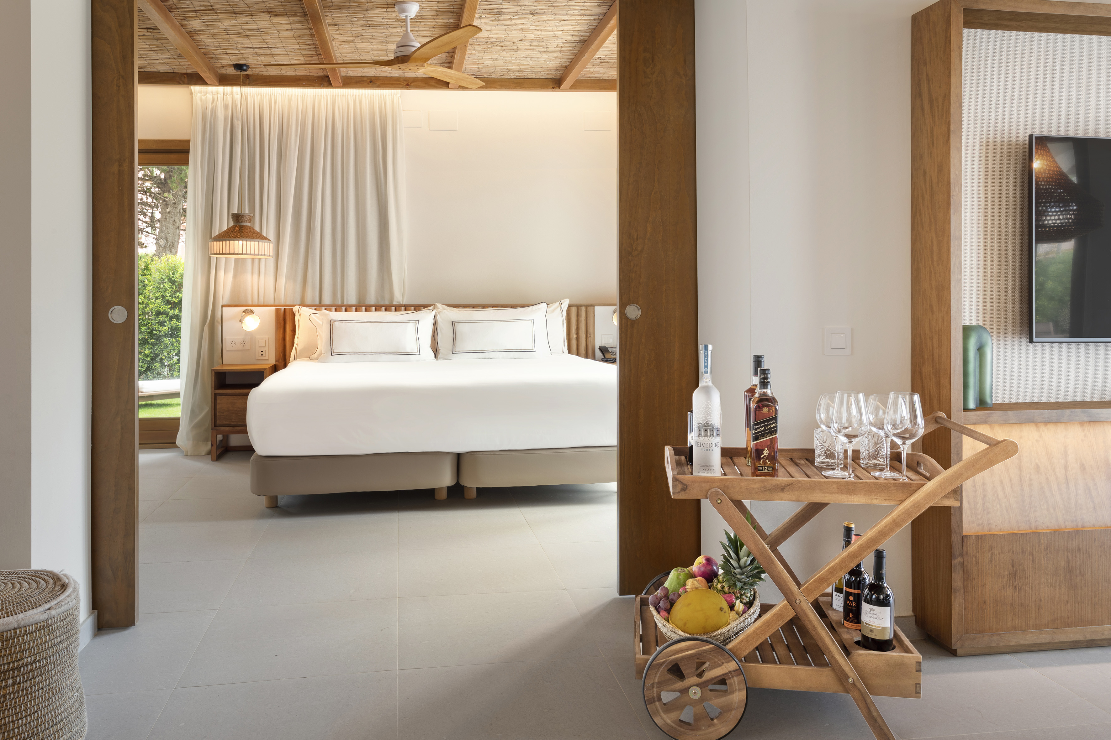 a room with a bed and a cart with wine bottles and glasses